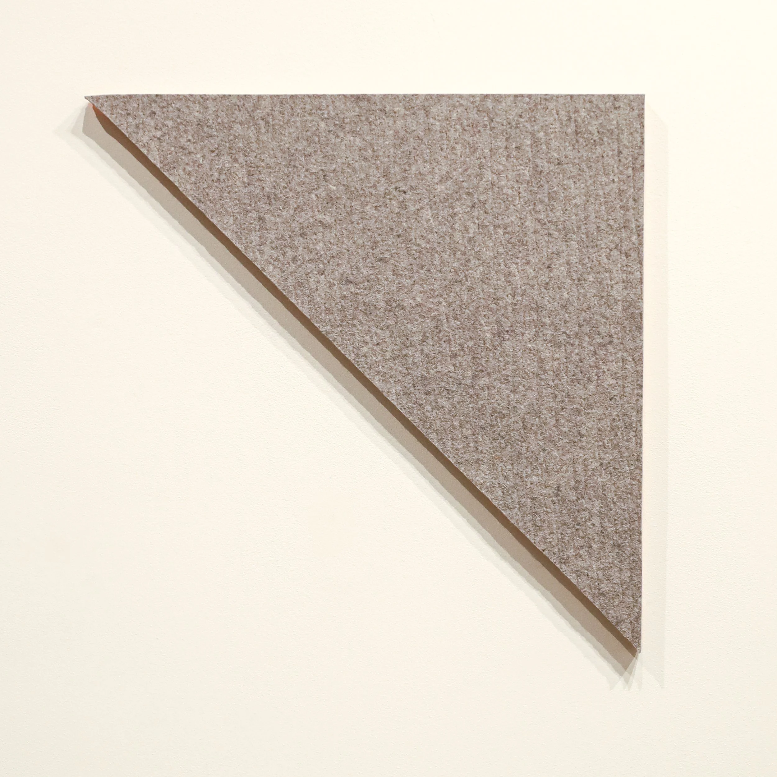 A textured gray triangular felt board mounted on a white wall.