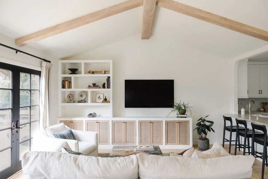 A contemporary living room showcasing white furniture complemented by wooden beams, enhancing the space's charm and warmth.
