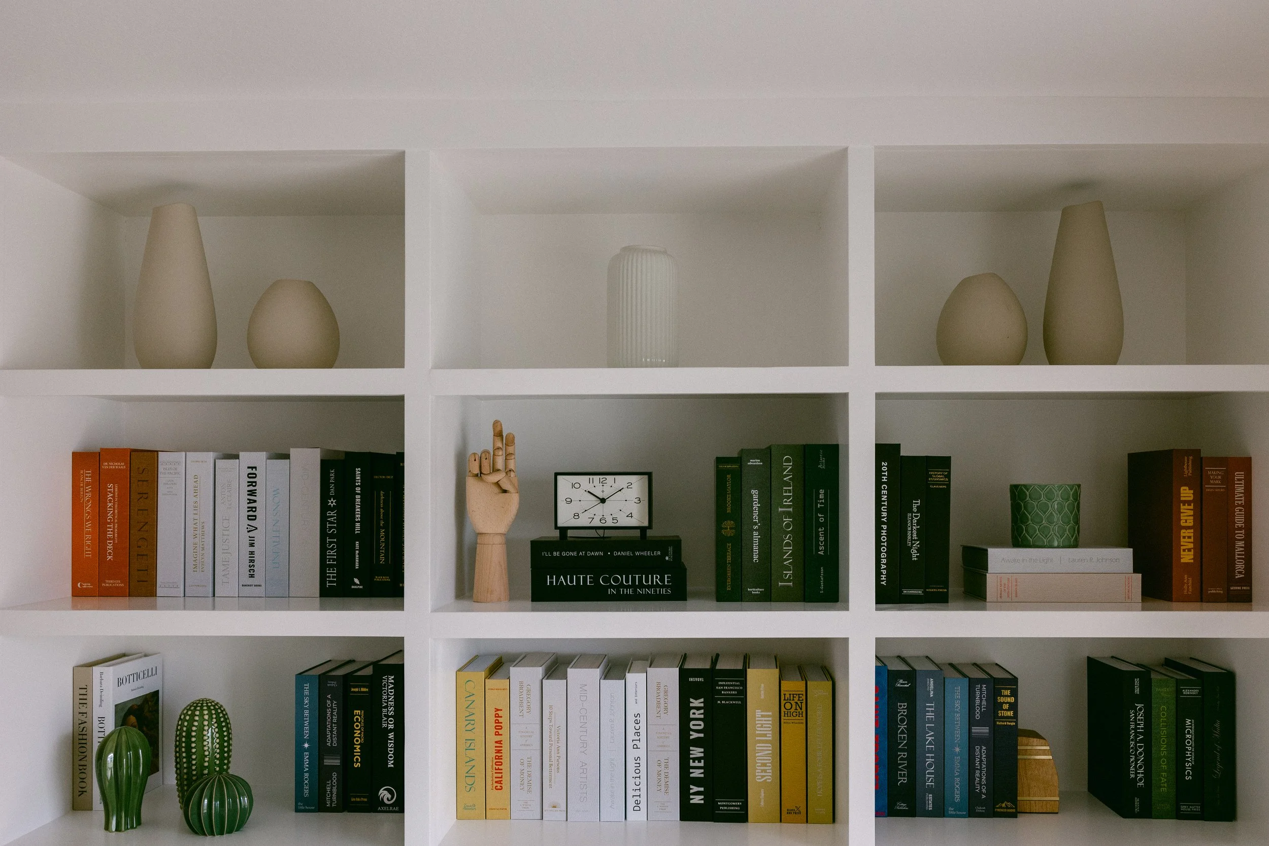 A white built-in bookcase featuring an array of books alongside decorative vases, enhancing the room's aesthetic appeal.