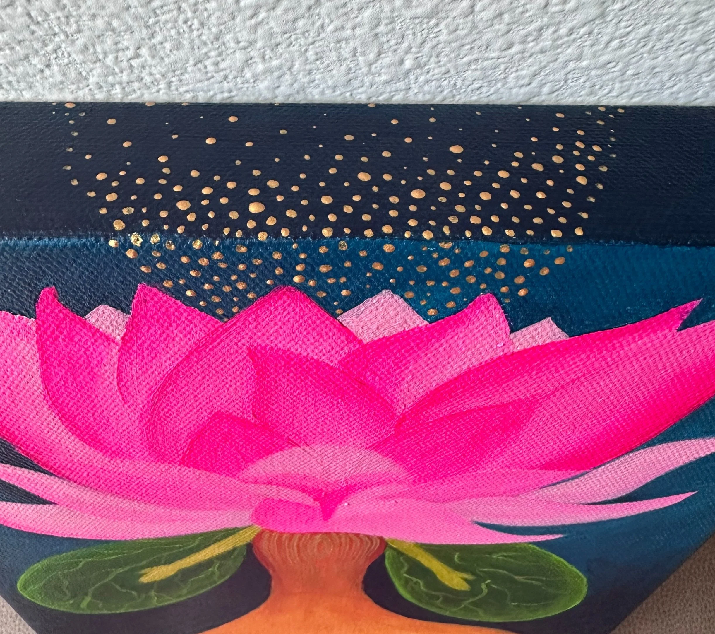 Close-up of a bag with a pink lotus flower design and gold dotted patterns on a dark blue background.