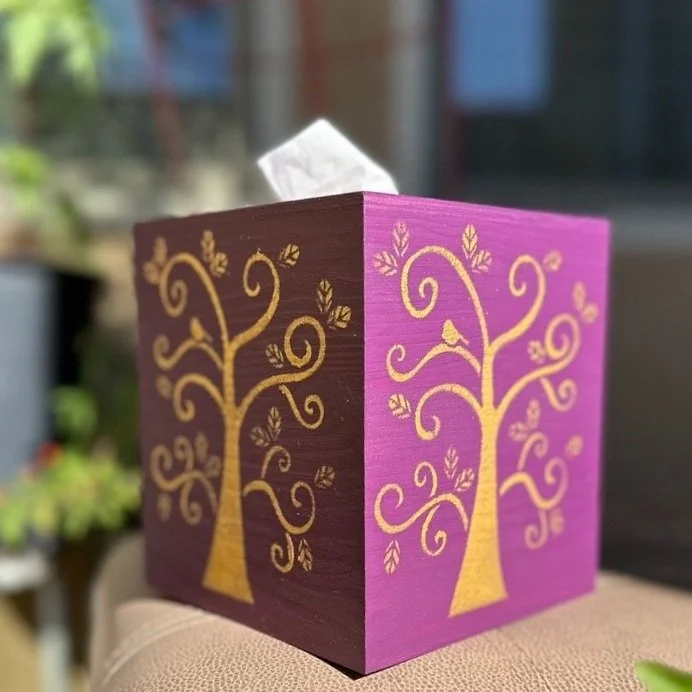 Decorative tissue box cover with painted trees in purple and brown colors.