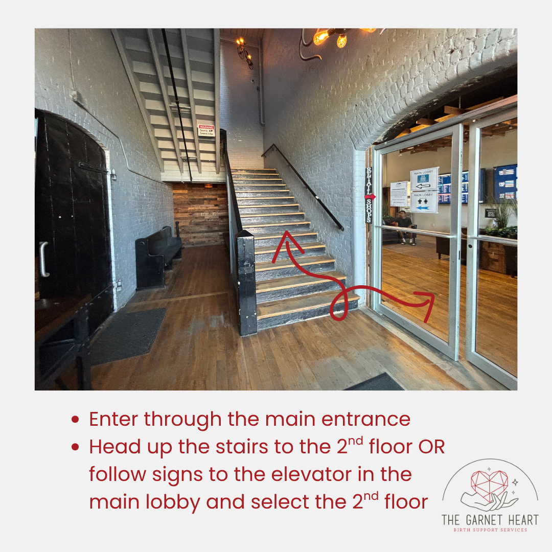 Photo of the front entrance interior of the Kilburn Mill. Includes arrows showing ways to get to The Garnet Heart office space - up the stairs or through the glass doors to get to the elevator.