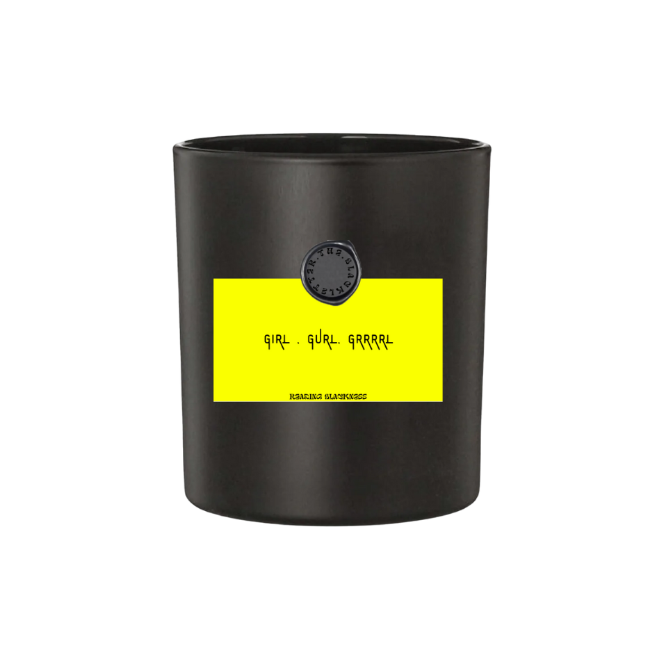 Black candle jar with yellow label reading 'GIRL, GURL, GRRRL' in stylized text, possibly a product from Raging Blk Brand.