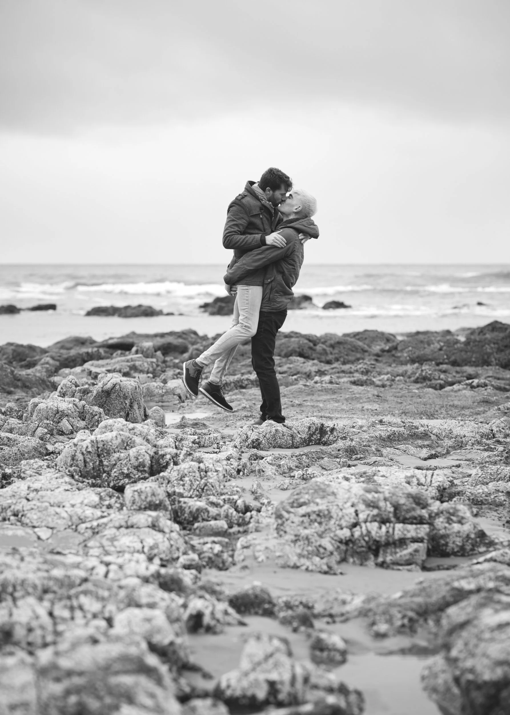 A couple kisses each other at a couples LGBTQ+ photoshoot during low tide on the Oregon Coast.