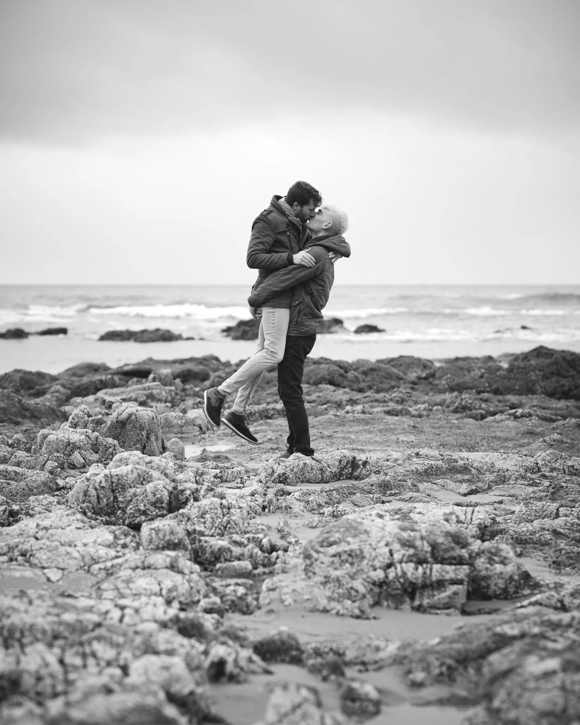 A gay couple kisses each other at a couples photoshoot during low tide on the Oregon Coast.