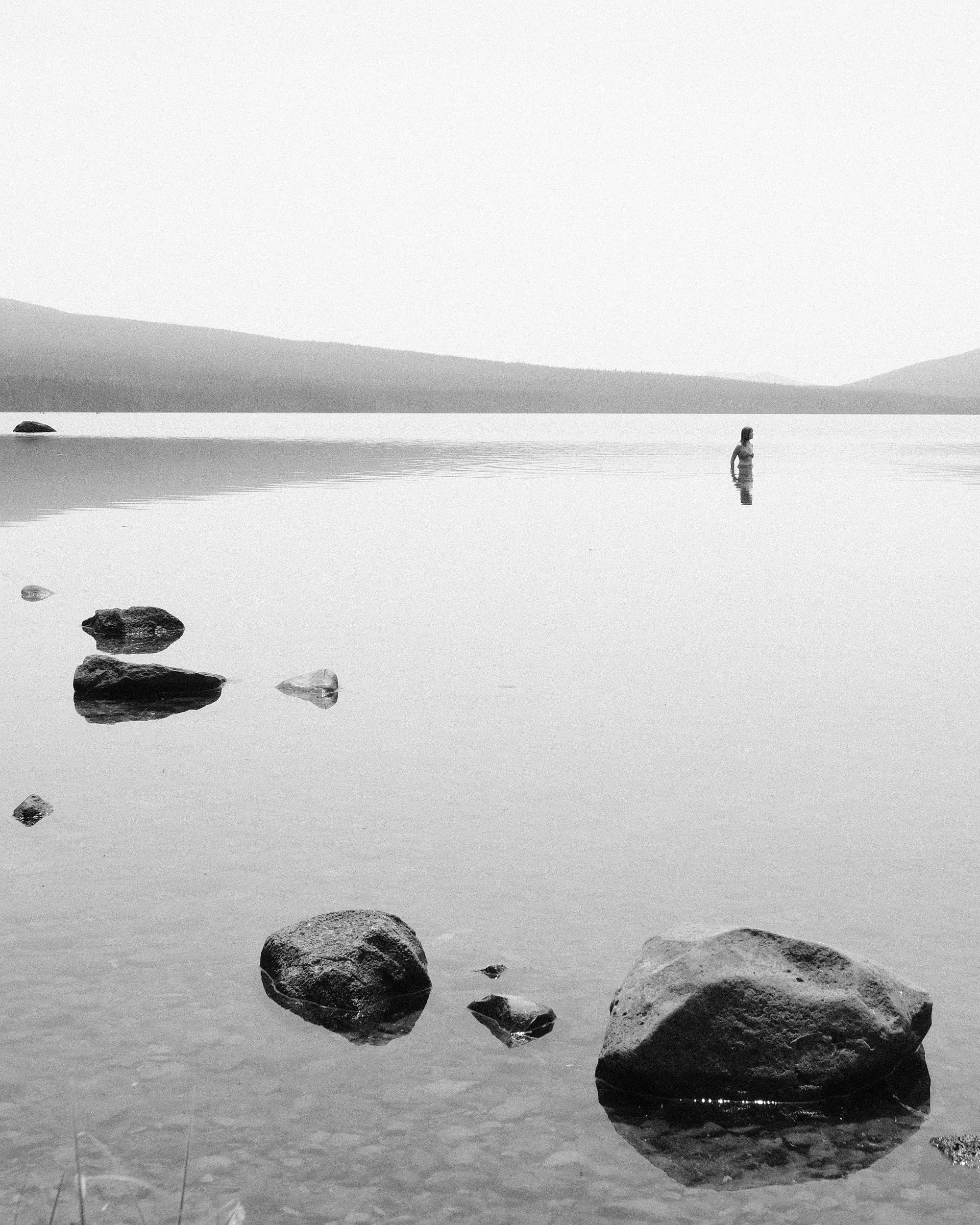 A woman swims in Waldo Lake Oregon with wildfire smoke creating a haze.