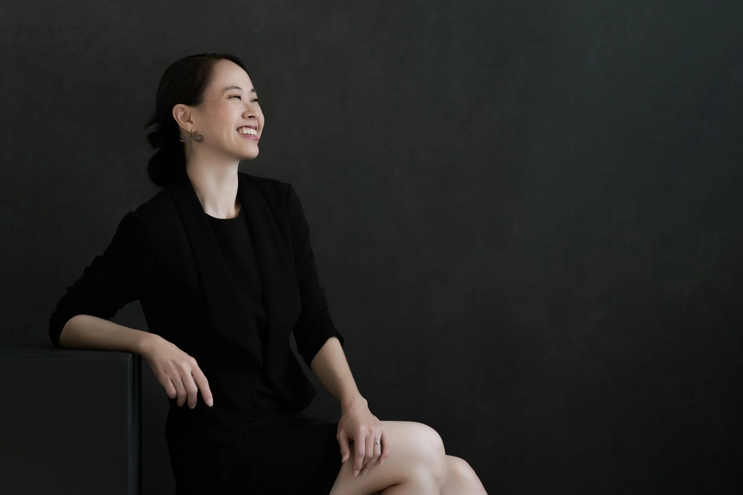 Portrait of Julia Morizawa sitting to left against a dark background.