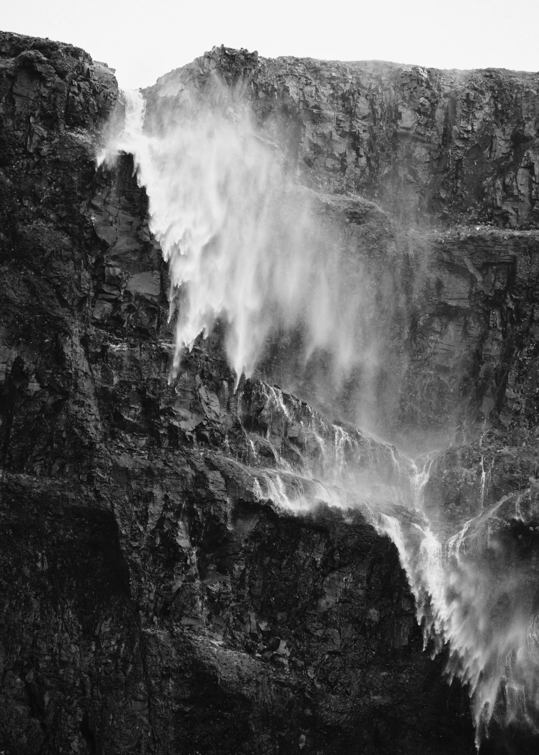 Iceland waterfall appearing to flow upward due to strong winds blowing up the fjord in the Westfjords.