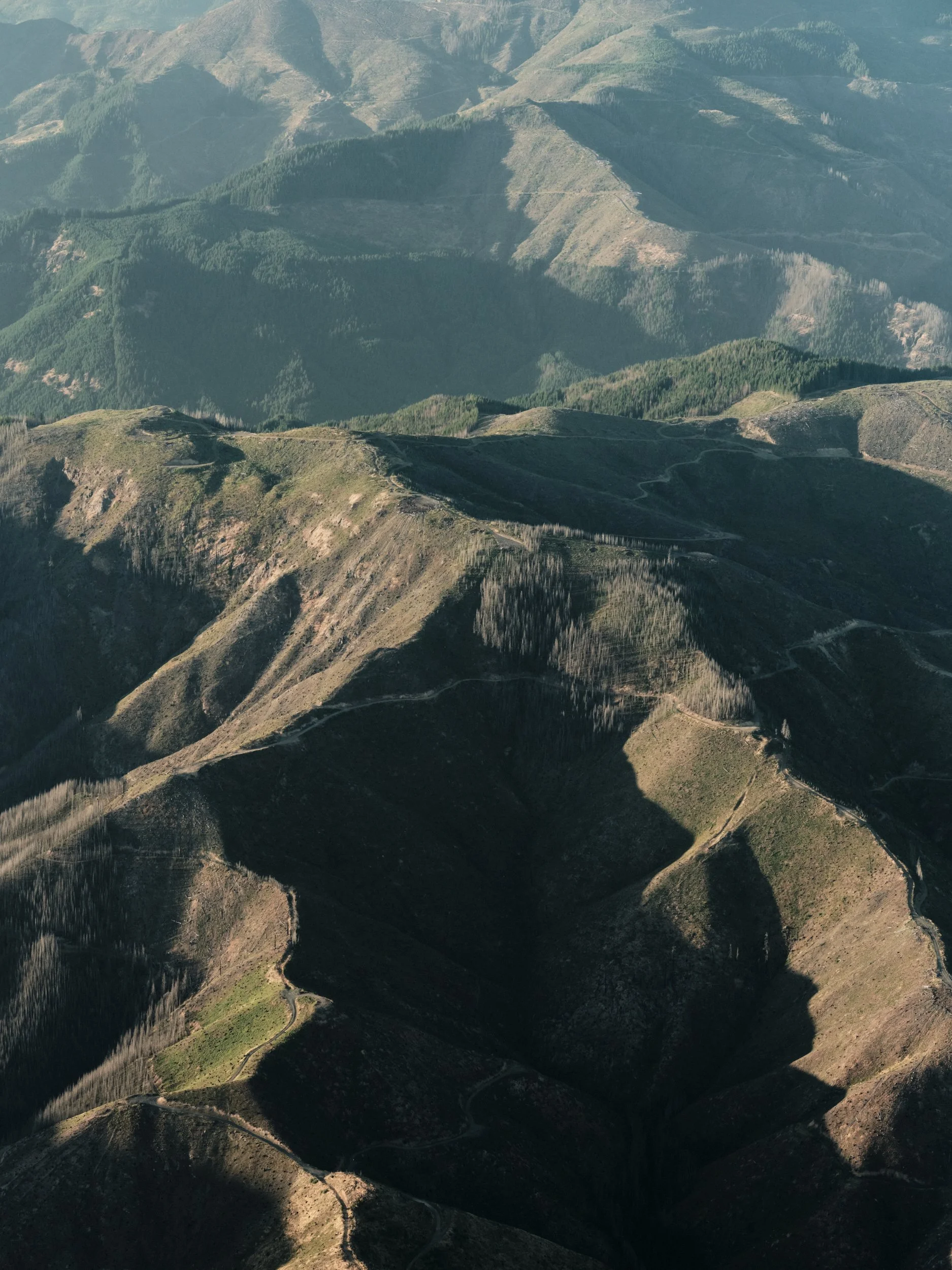 Aerial view of a rugged mountainous landscape in Oregon with rolling hills and deforested land. 