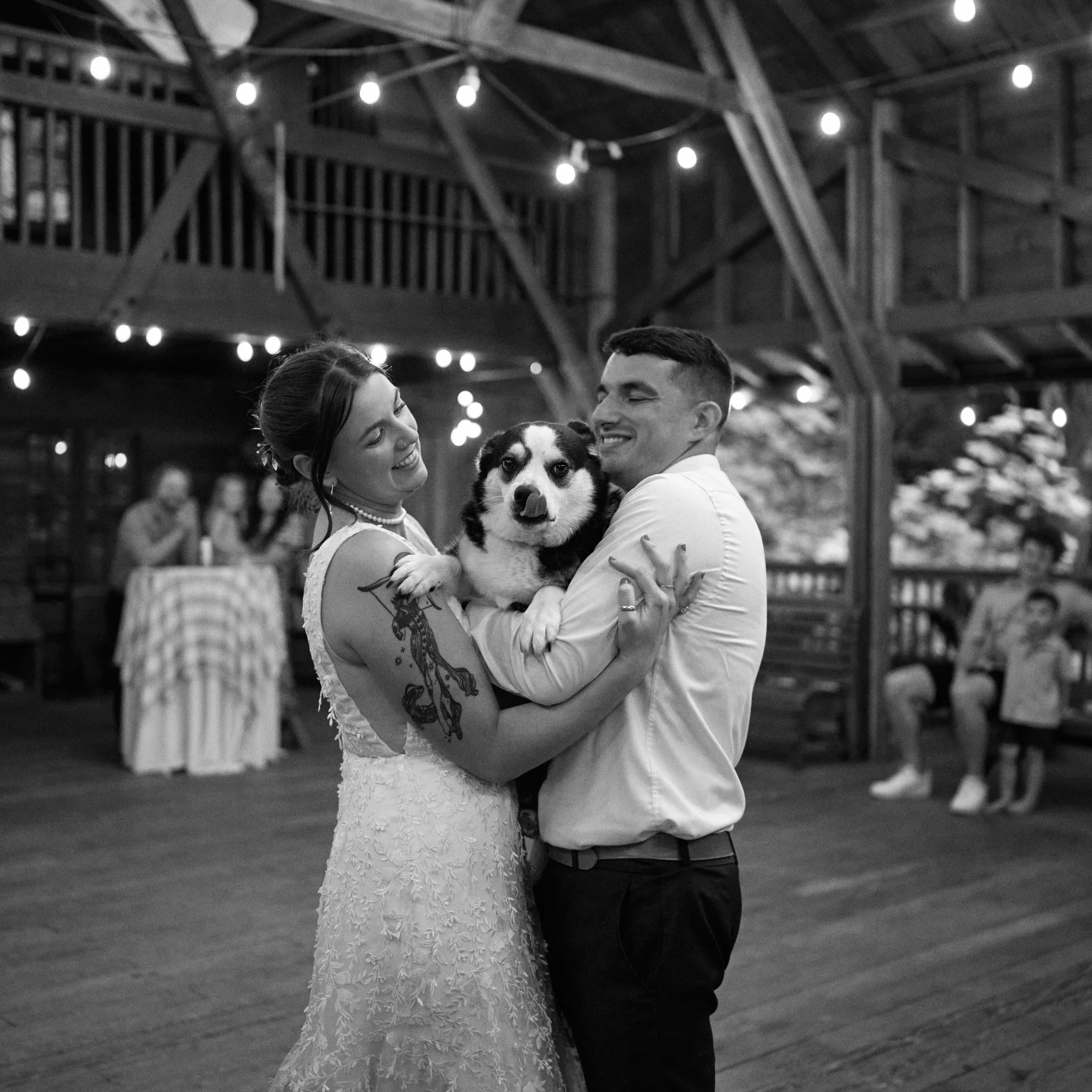A bride and groom hold their corgi/Australian Shepard dog during their first dance at Camp Namanu Oren. 