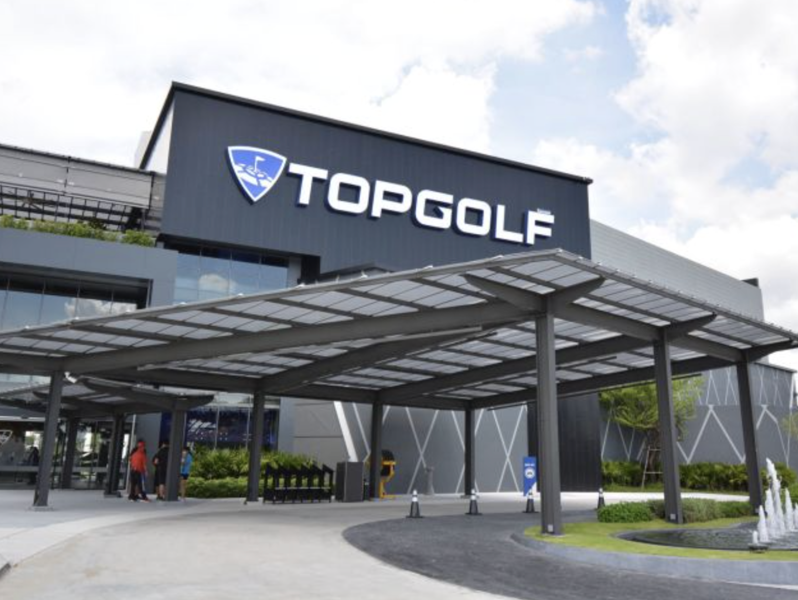 Exterior of Topgolf entertainment venue with a modern building and a large sign displaying the Topgolf logo and name.