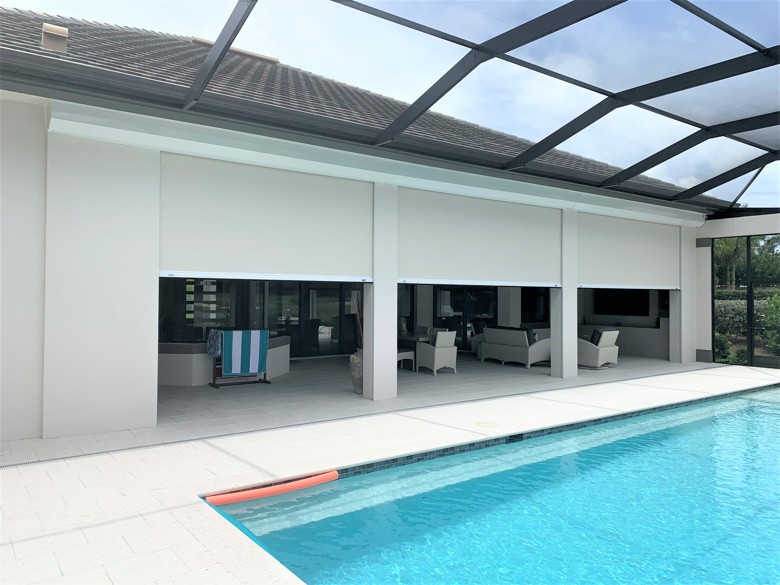 View of a backyard swimming pool with a covered patio area, outdoor furniture, and a house with a screened porch.