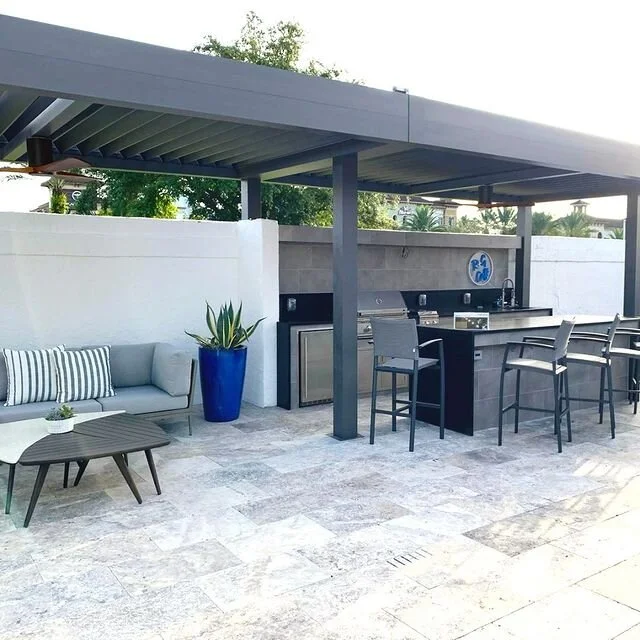 Outdoor patio with pergola, lounge area, and bar counter with stools, tiled floor, and potted plants.