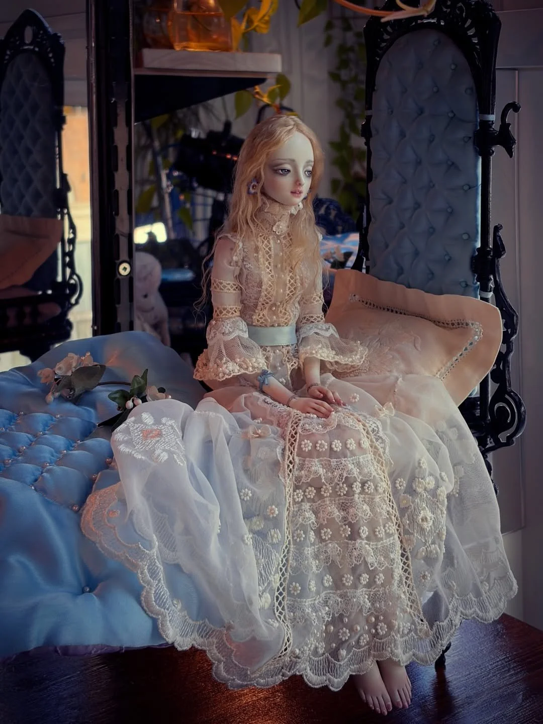a doll in a lace gown sits on a blue and black gothic bed