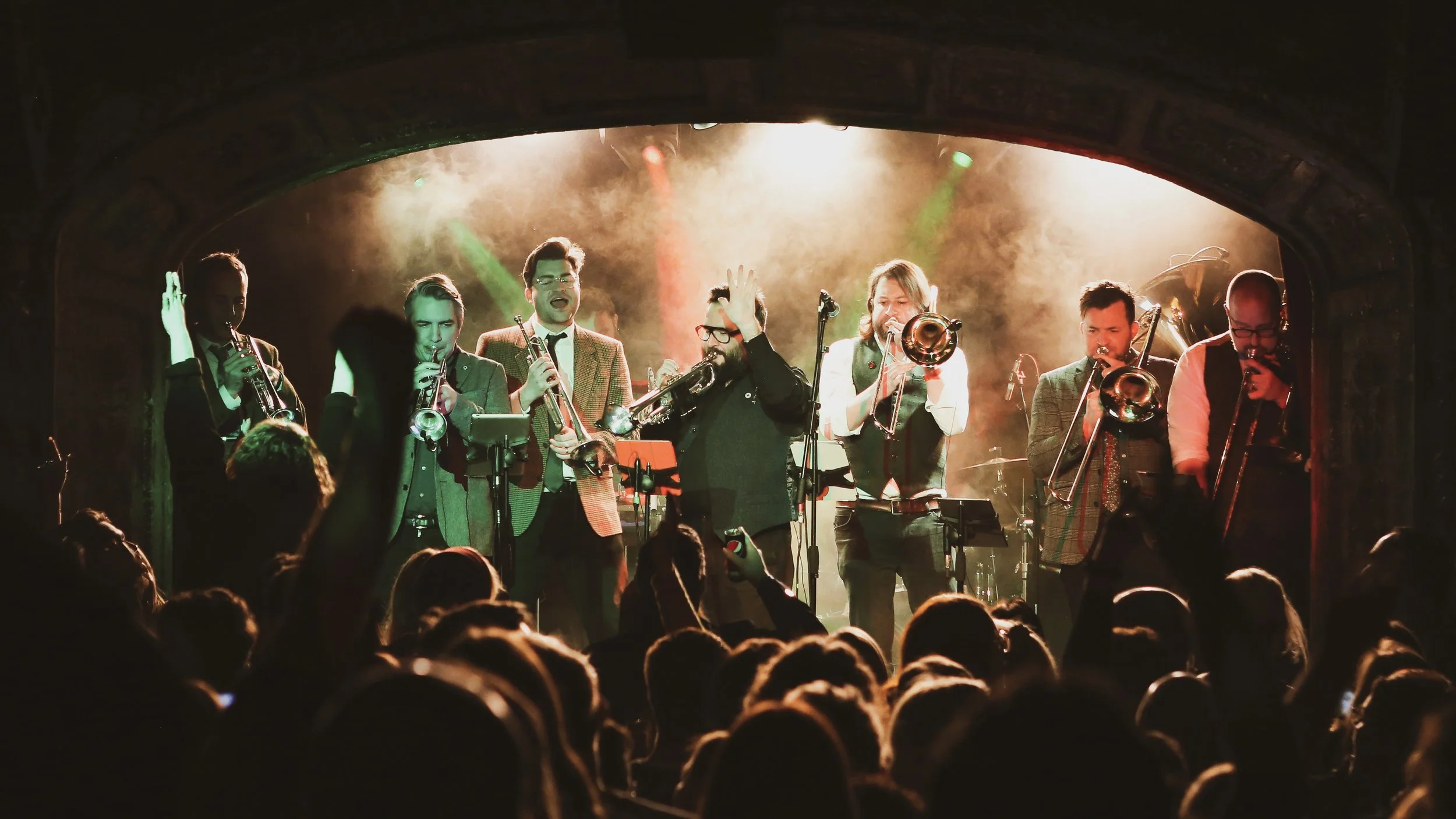 Jazz band performing on stage with colorful lights, and audience in front