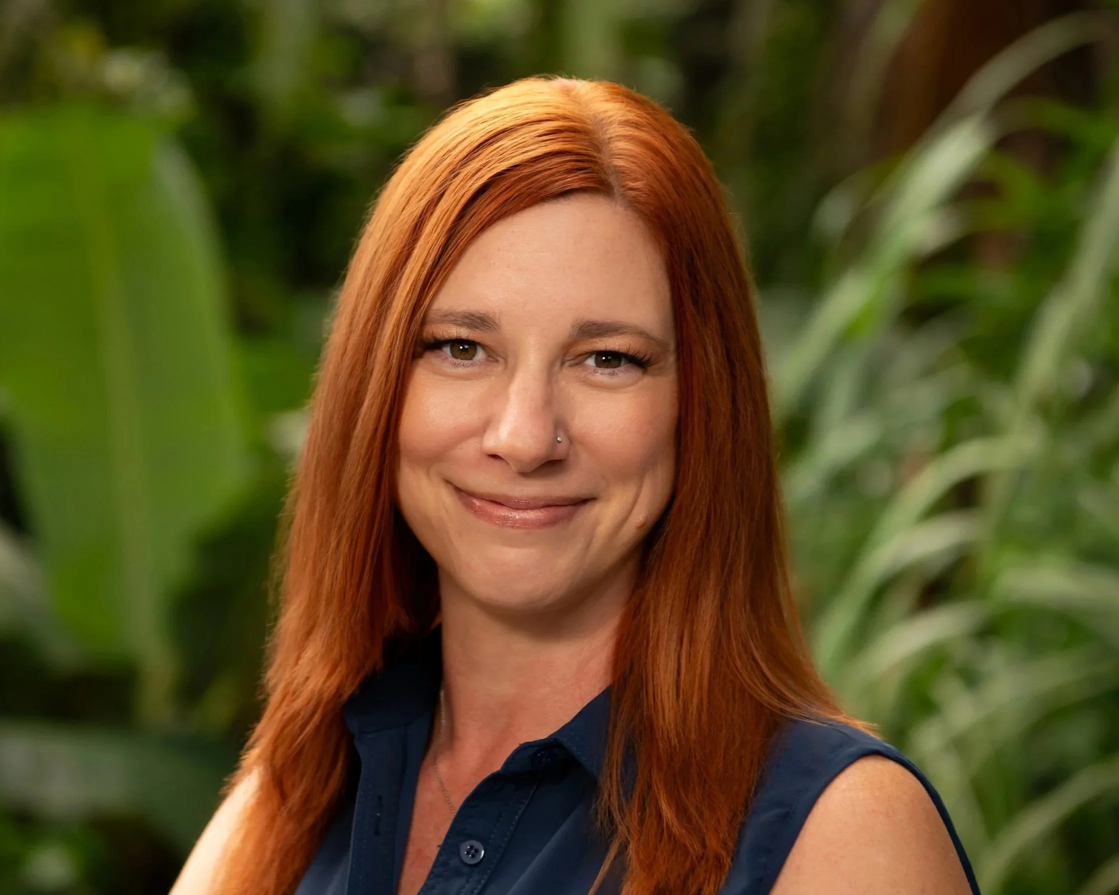 Woman with long red hair drinking from a dark coffee cup at an outdoor cafe