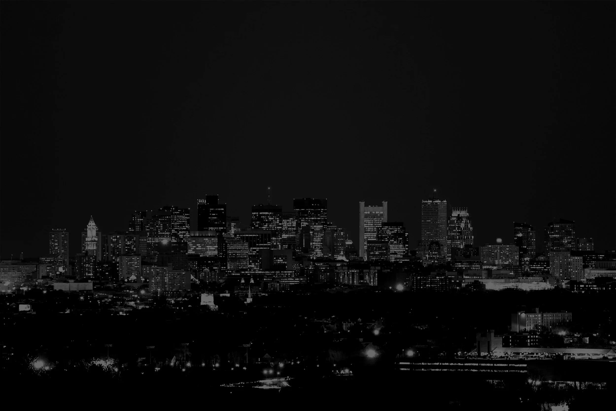Nighttime city skyline with illuminated buildings and dark sky.