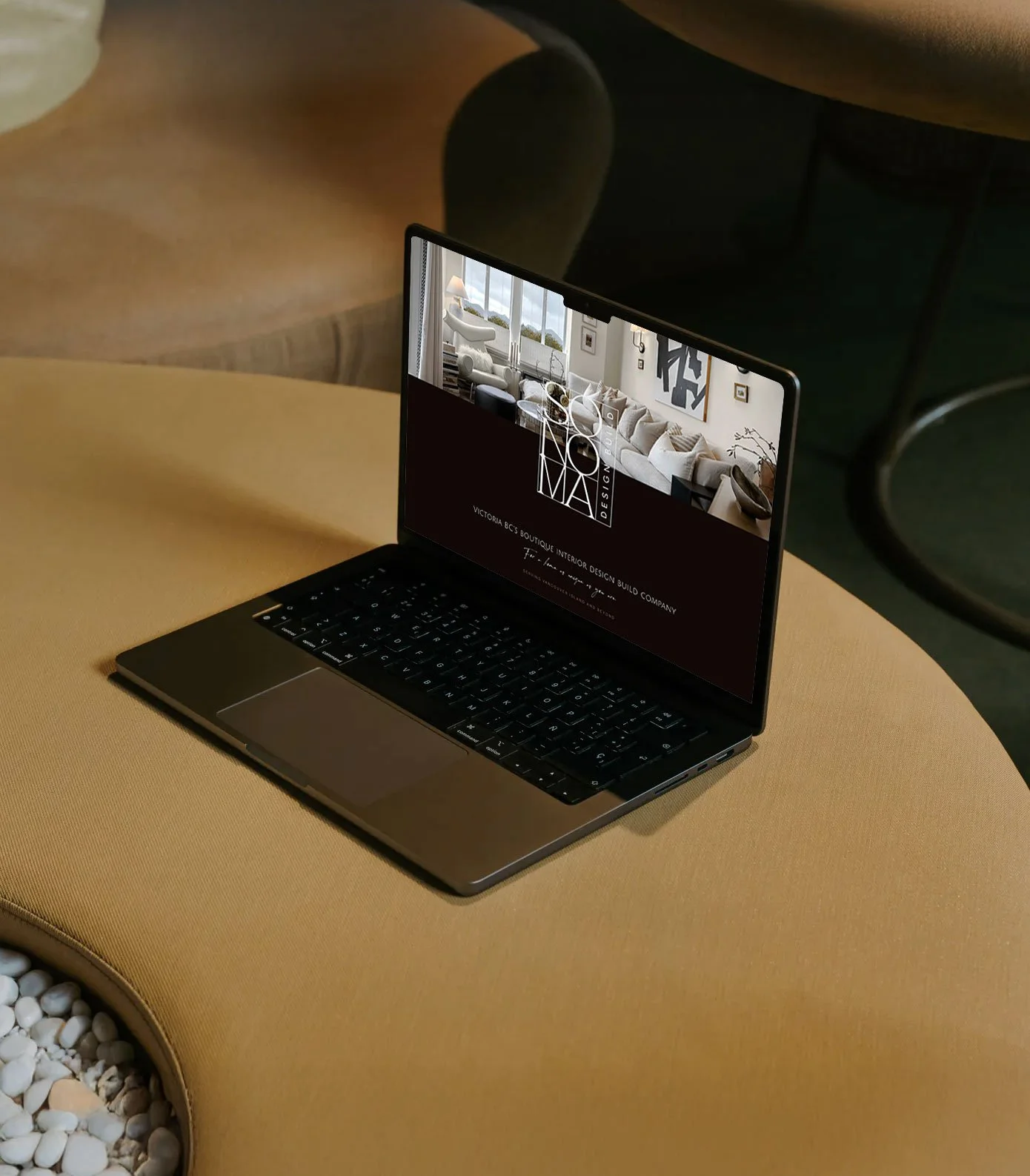 Open laptop on a yellow table showing a website for interior design, with furniture images and text.