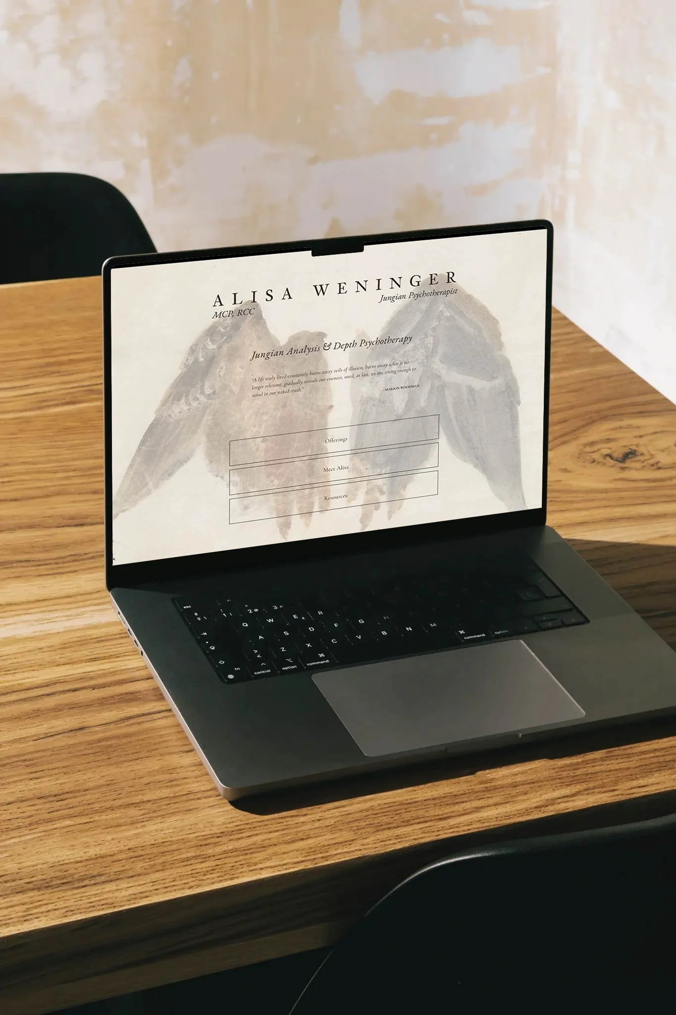 Laptop on wooden desk displaying a resume for Alisa Weninger, Jungian psychoanalyst, with mountains and eagle graphic in background.