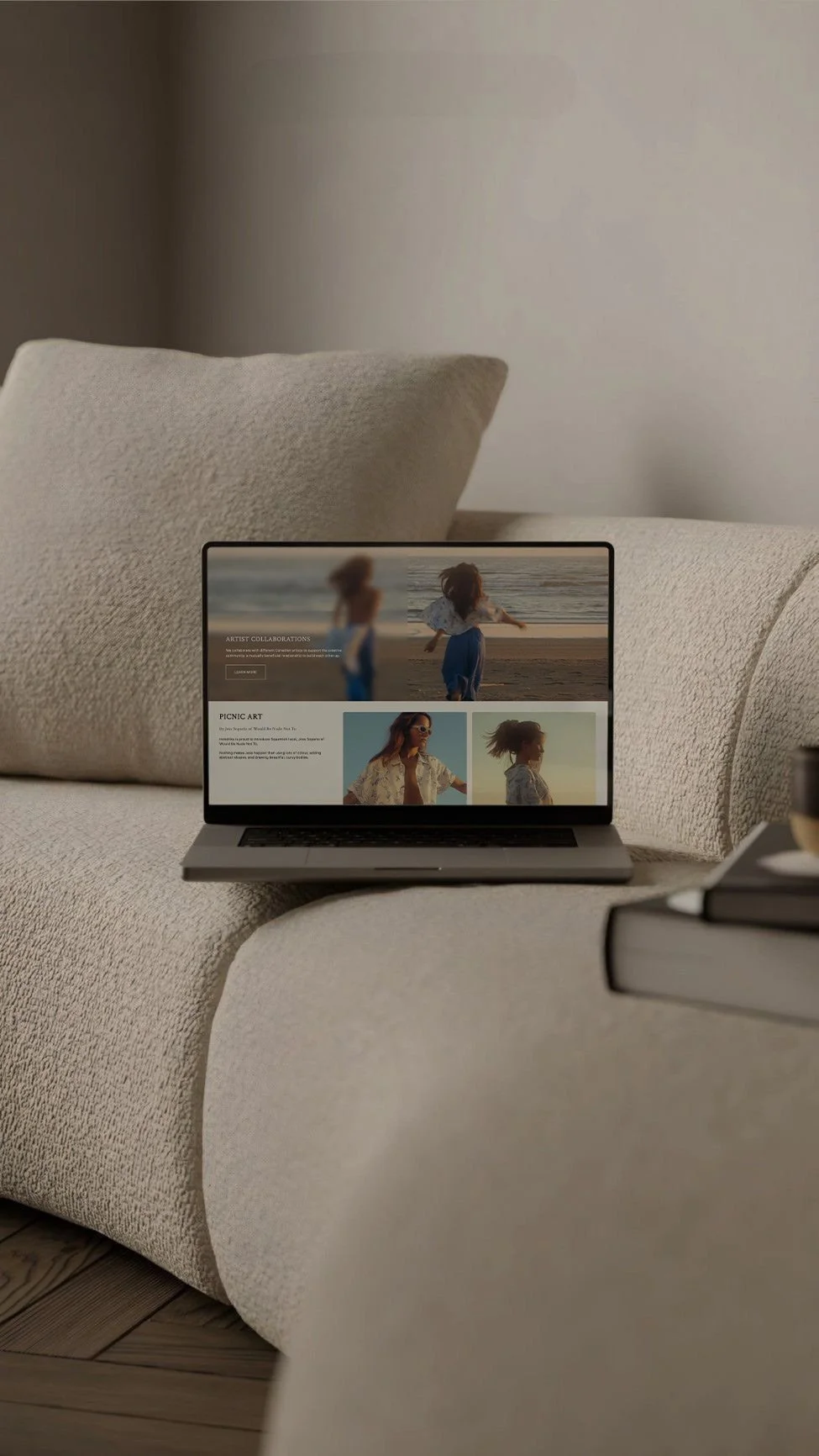 Open laptop on a beige sofa displaying a photography website featuring images of a woman and a girl at the beach.
