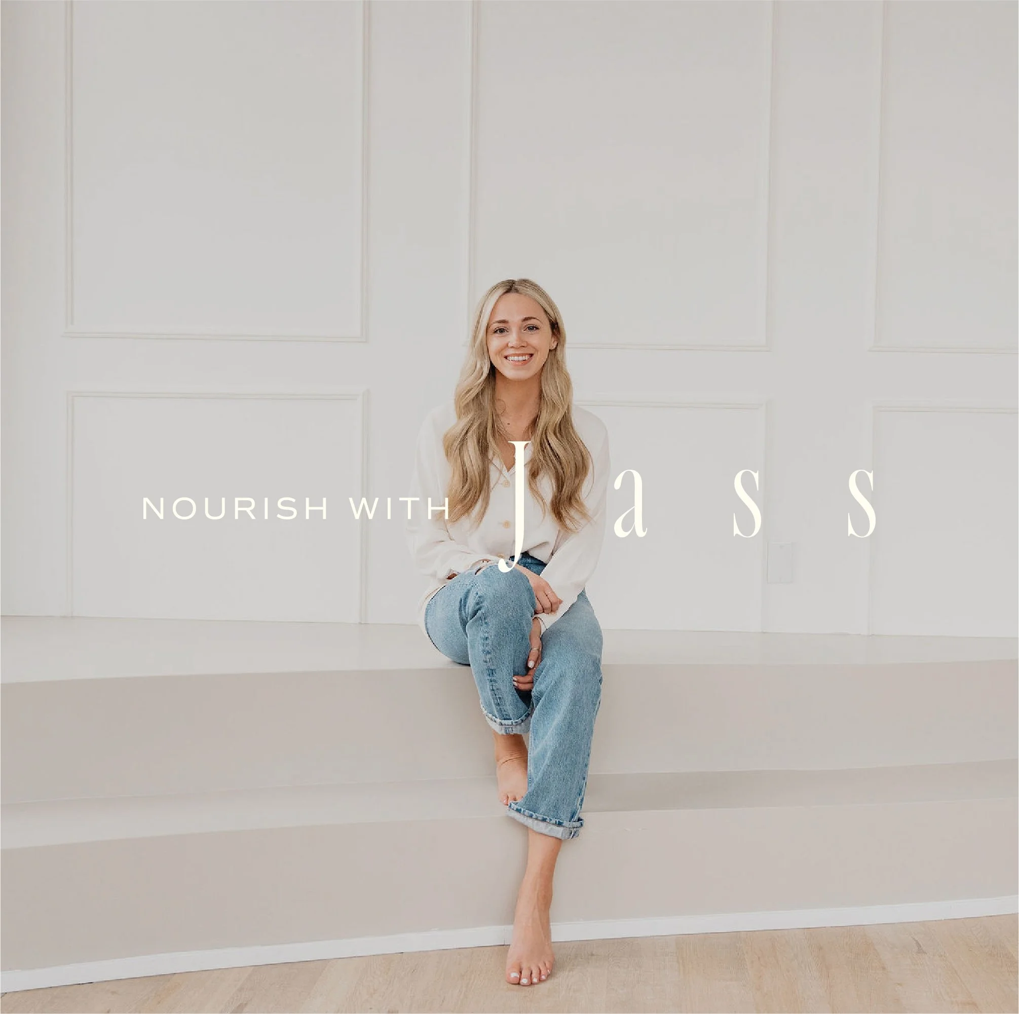 A woman with long blonde hair, smiling, sitting barefoot on a white ledge in a minimalist white room with paneling, wearing a white shirt and blue jeans, with text overlay 'Nourish with a S S'.