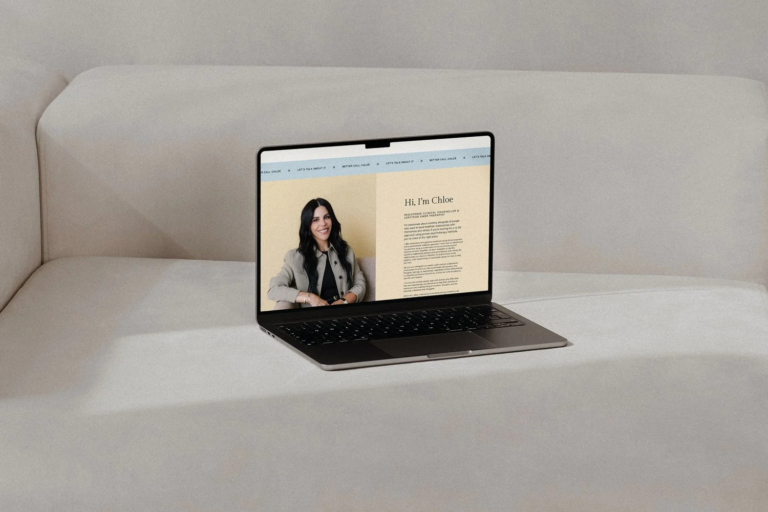 Laptop displaying a personal website with a photo of a woman and introductory text on a minimalist white surface.