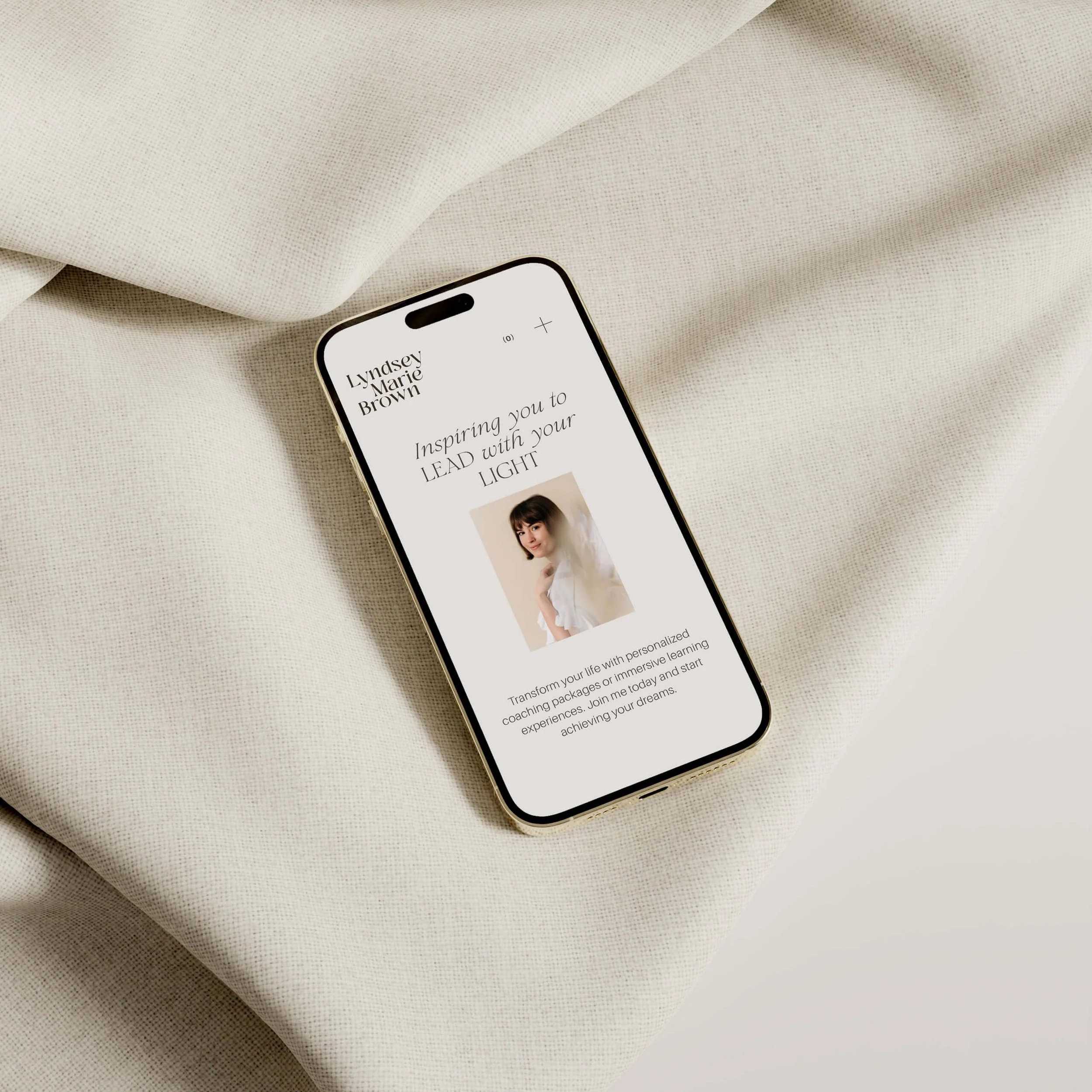 Smartphone displaying a website with text and a photo of a woman, resting on a beige fabric surface.