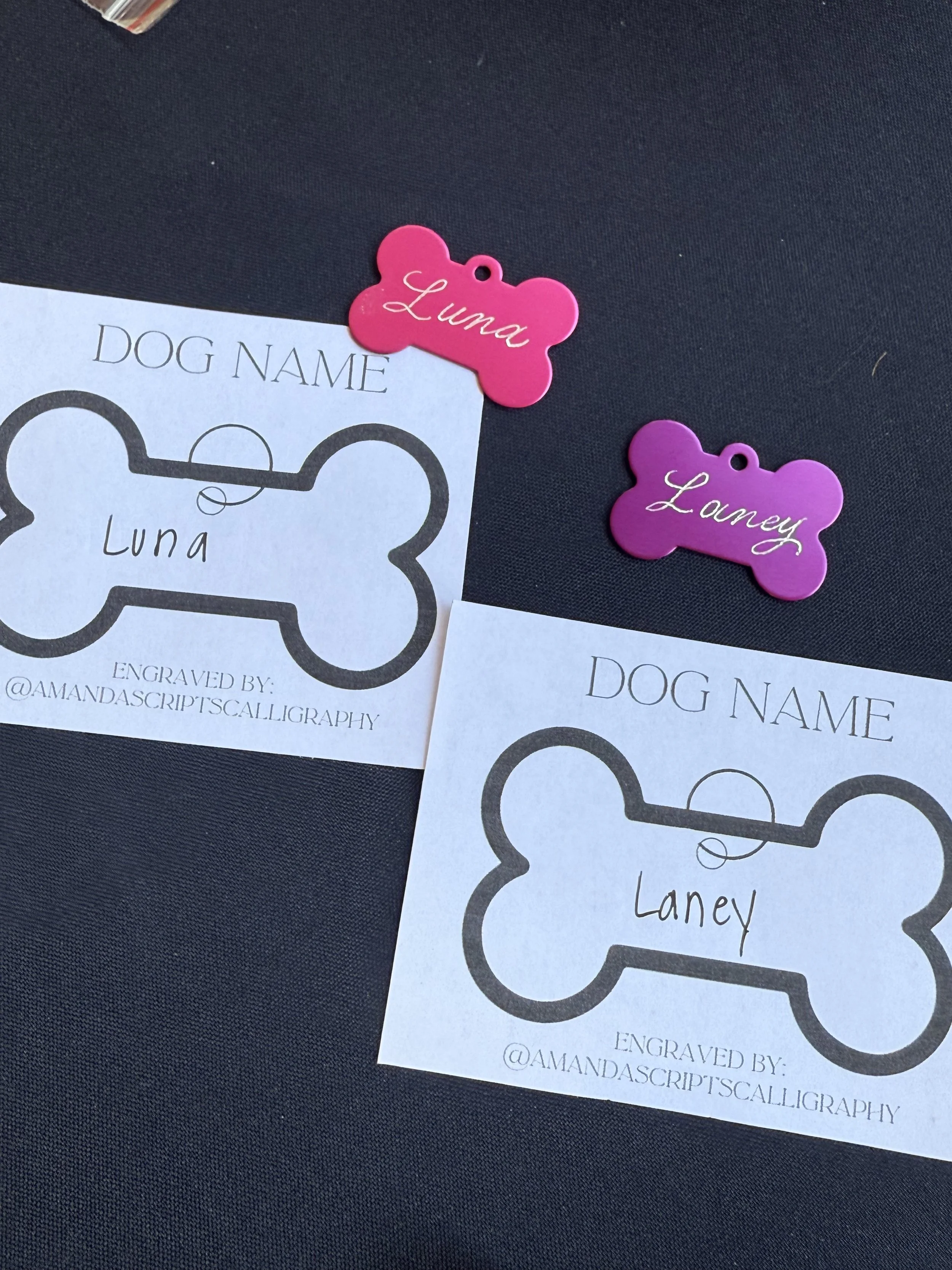 picture of a pink and purple metal dog tag that was hand engraved. The request cards are also included in the photo