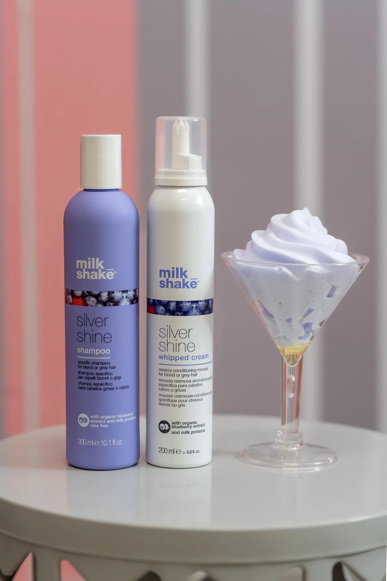 Two bottles of Milk Shake Silver Shine hair products, a purple shampoo and a white whipped cream conditioner, sold exclusively at the best hair salon in the Mid-Cities, DFW, Moxxi Grey Salon in Colleyville, TX