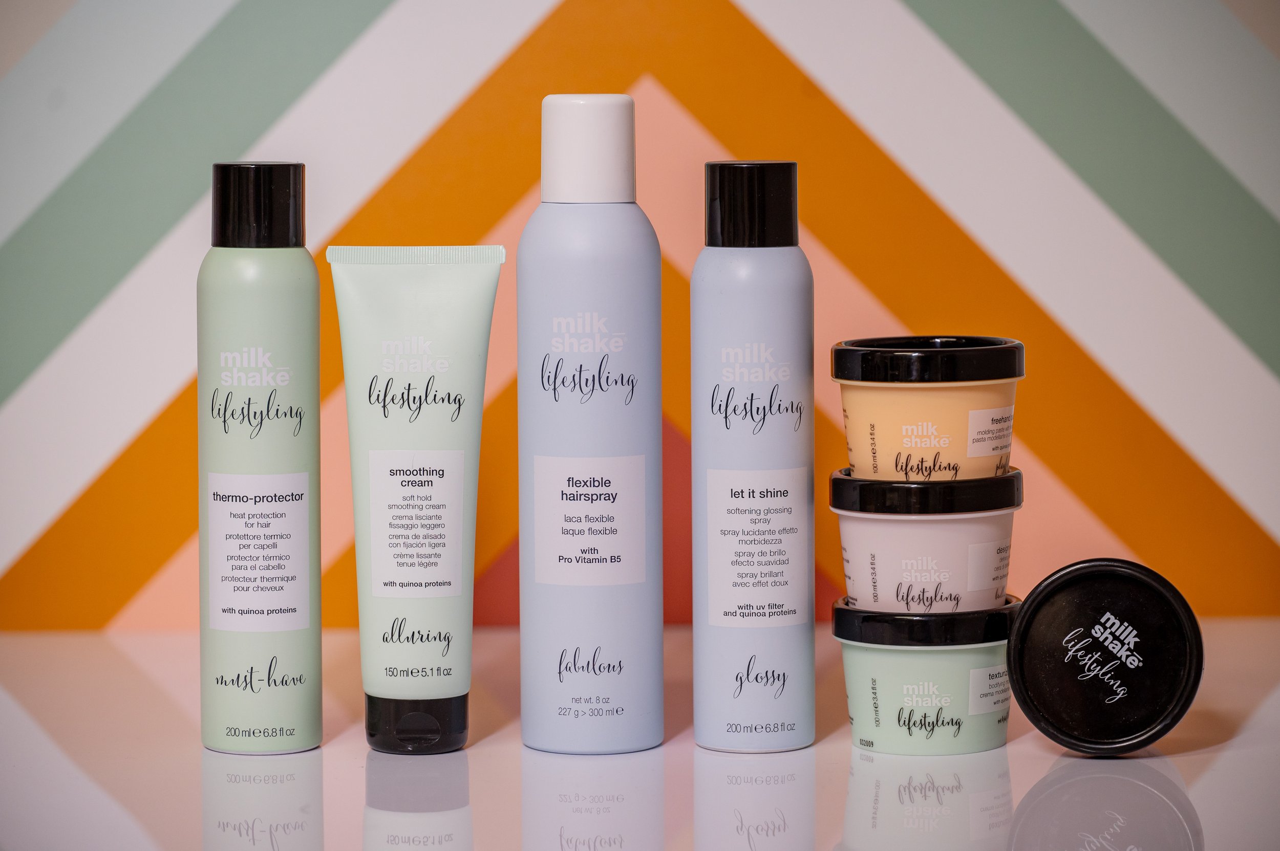 A collection of Milk Shake Lifestyles hair styling products, including thermo-protector, smoothing cream, flexible hairspray, let it shine spray, and more and Moxxi Grey Salon In Colleyville, TX