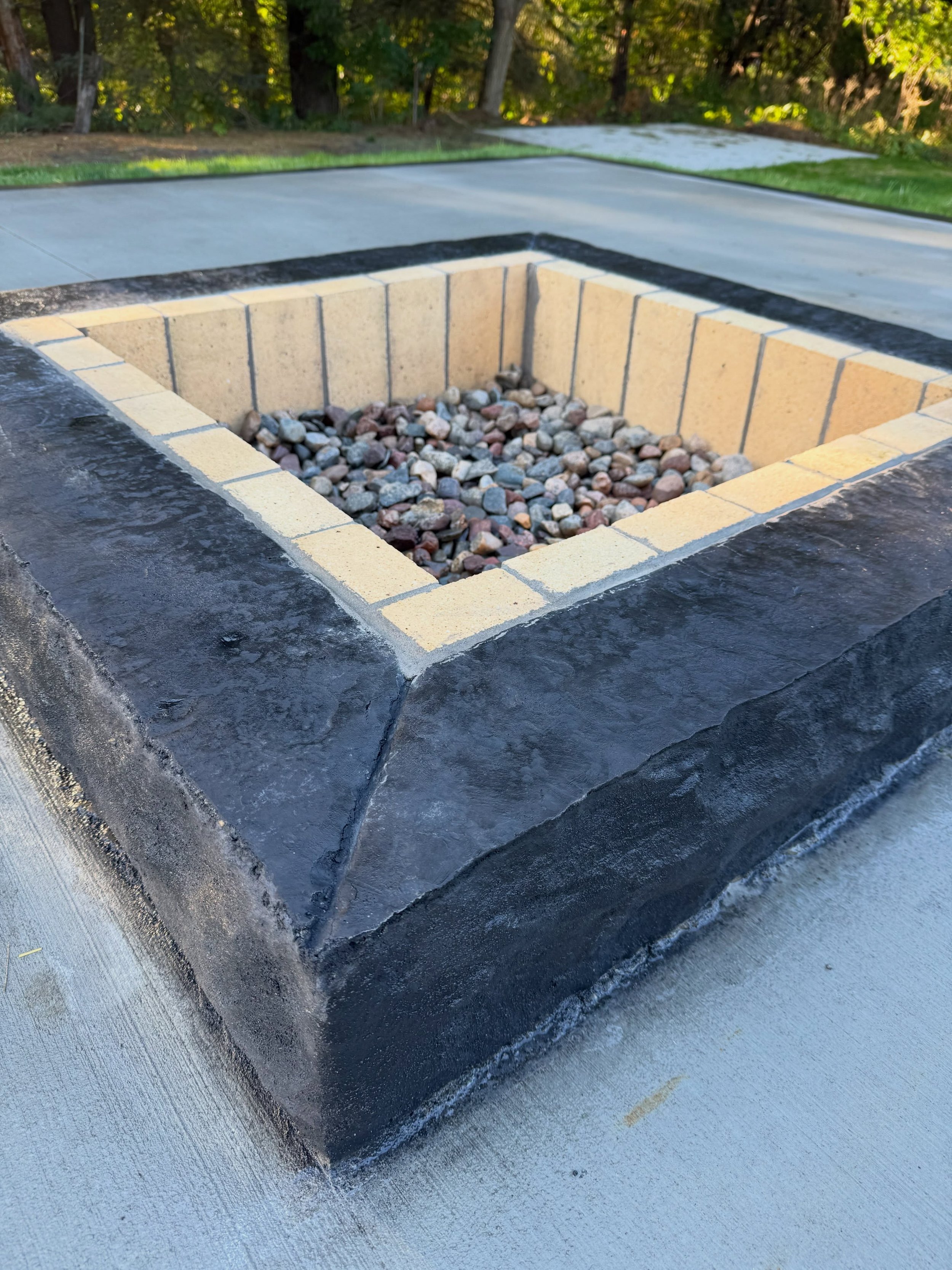 Black black fire pit with a black border patio. 🔥