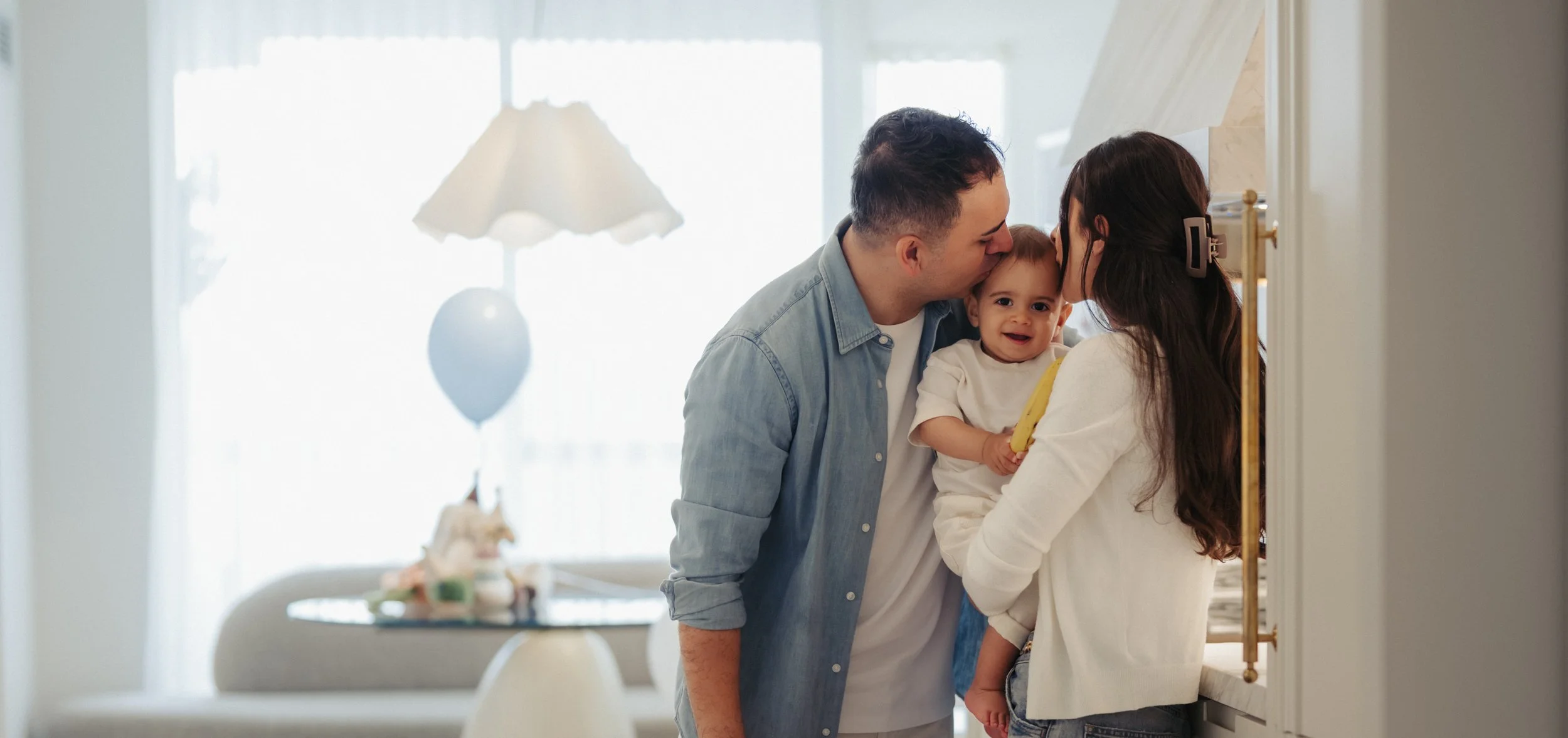 first-birthday-at-home-toronto-parents-kissing-baby-kitchen.jpg