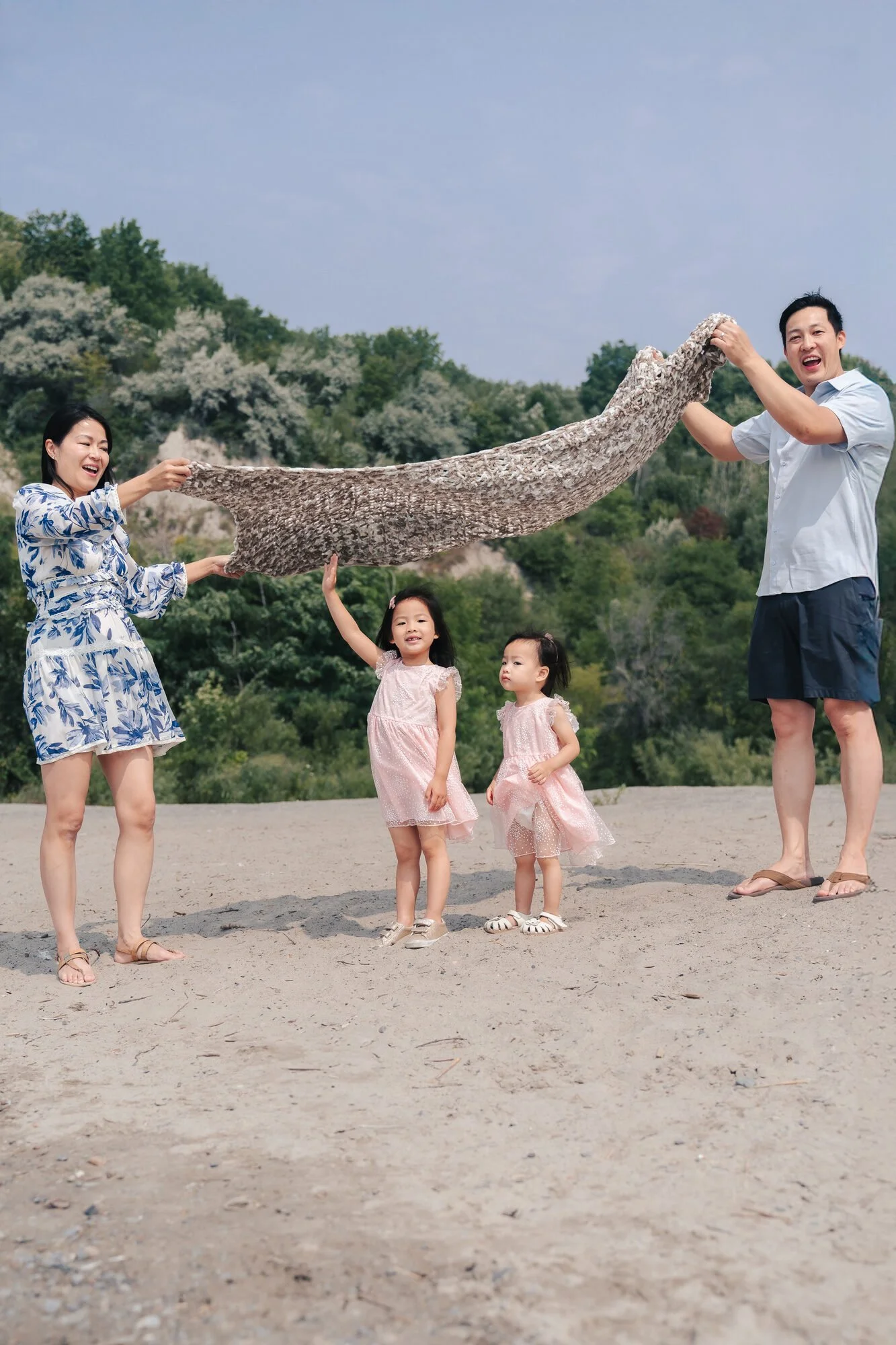 scarborough-bluffs-family-session-parents-holding-blanket-kids-playing.jpg