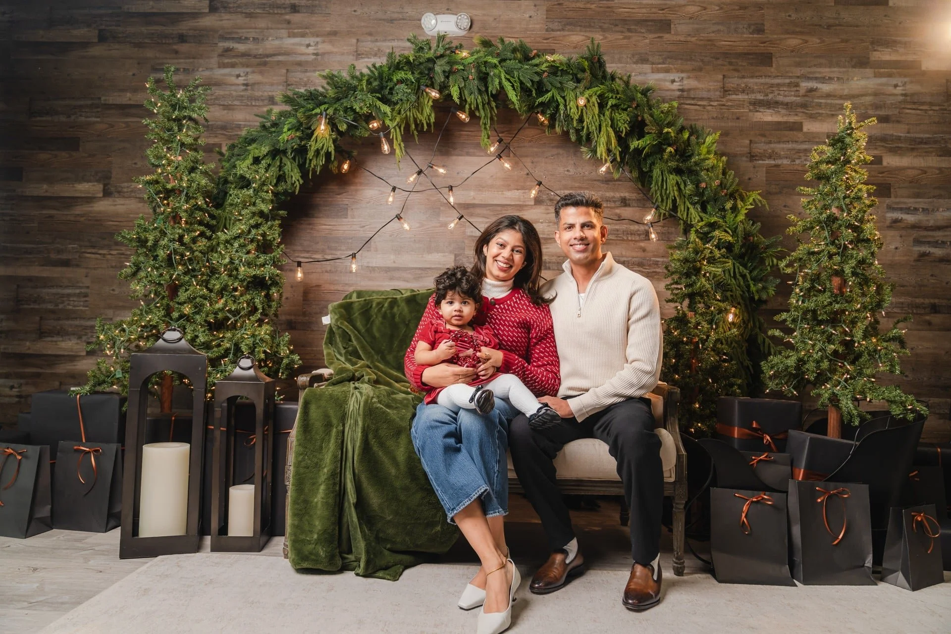 	Family Christmas photoshoot on a green velvet sofa under a greenery arch, Toronto