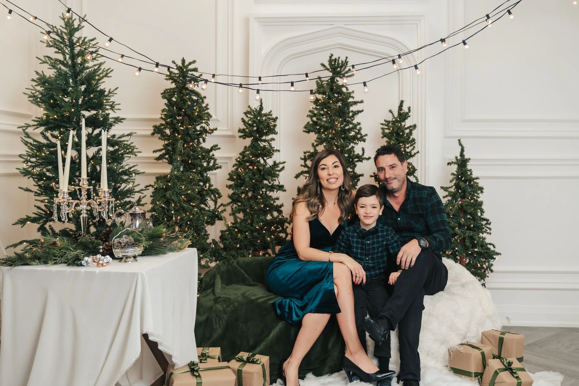 Family Christmas photoshoot on a green velvet sofa among evergreens, Toronto