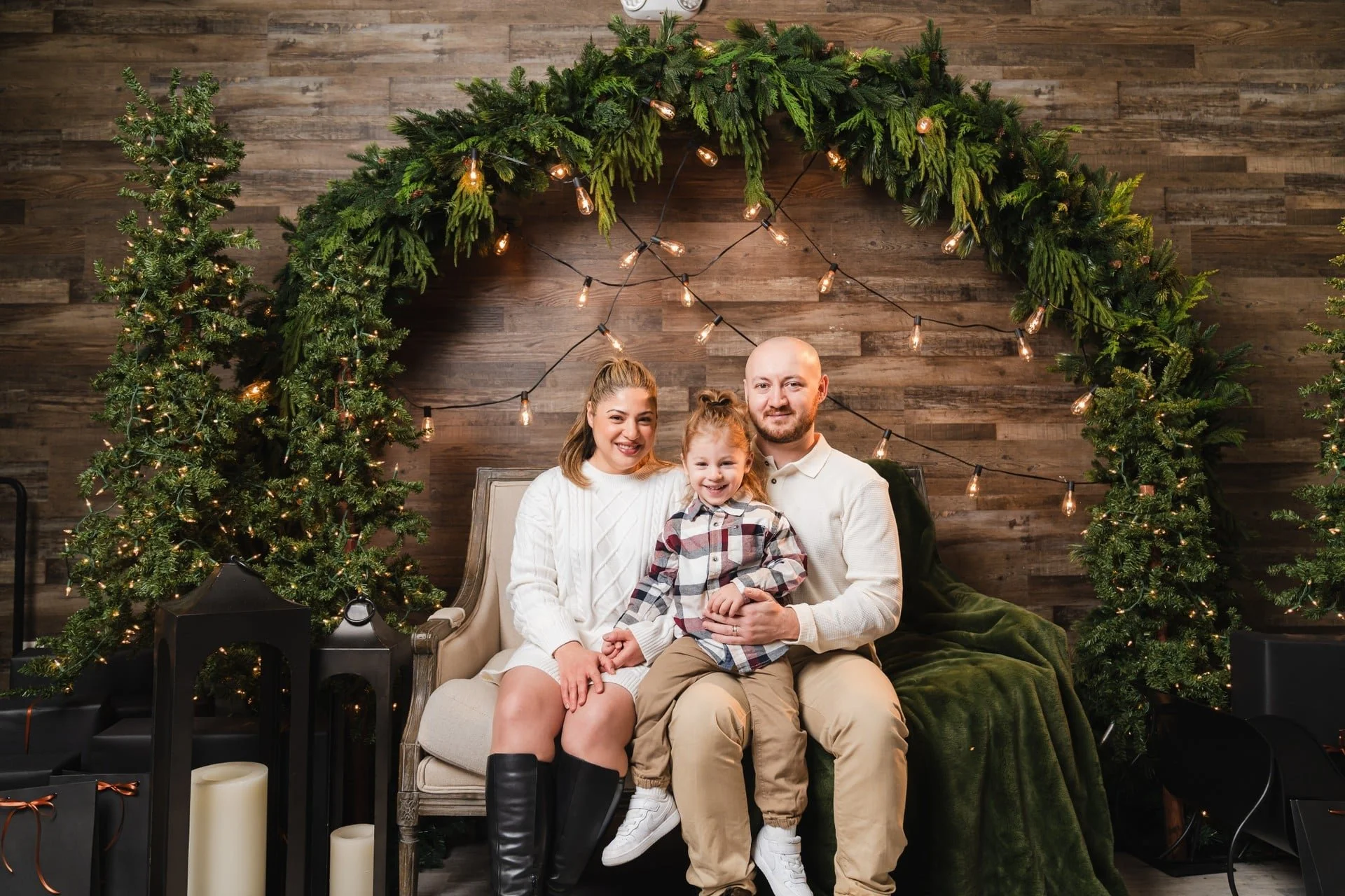 Family Christmas photoshoot on a green velvet sofa under a greenery arch, Toronto