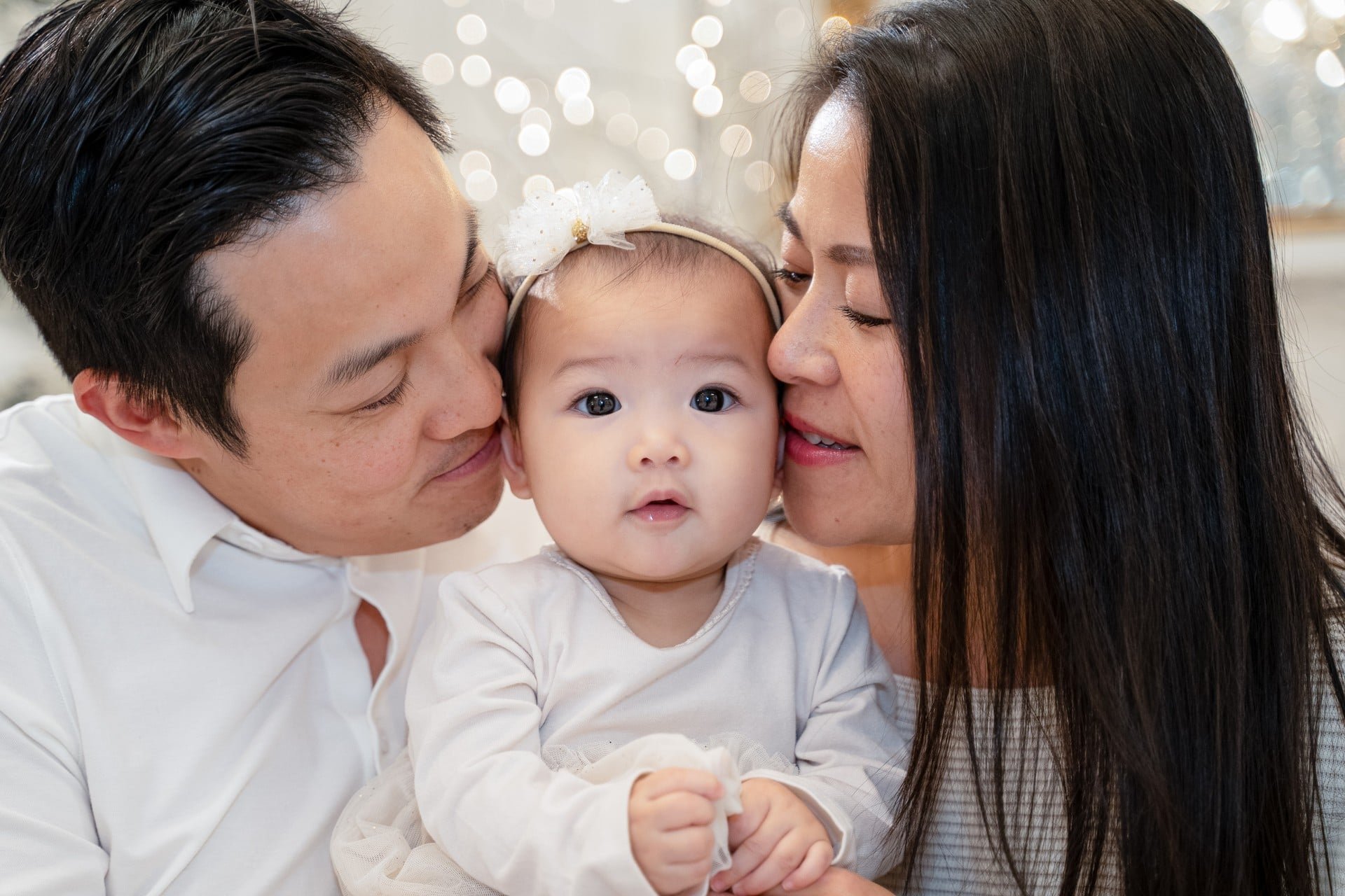 	Parents kissing their baby girl at a Toronto first Christmas photoshoot	