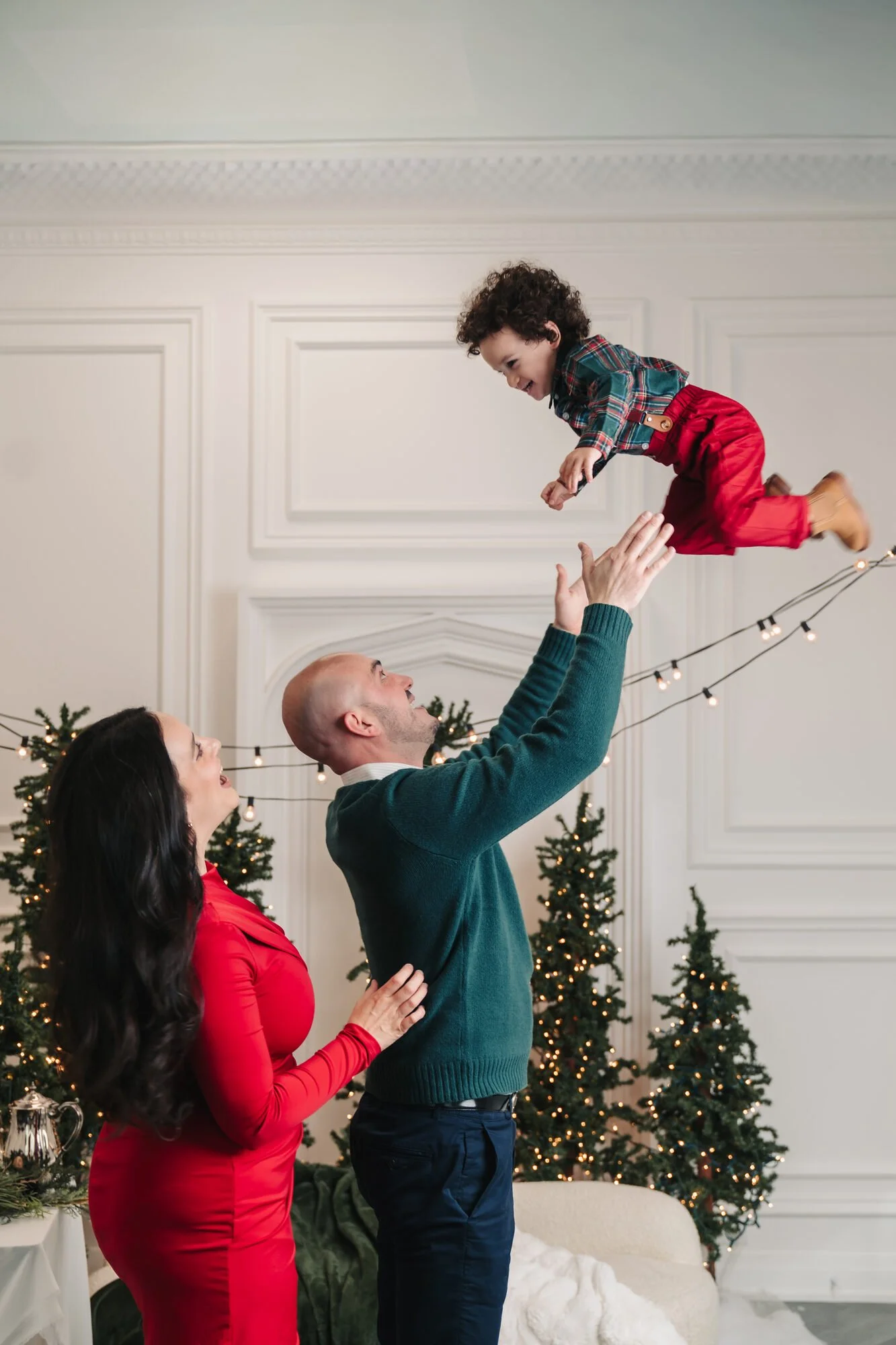 Dad lifting his laughing toddler at a candid Christmas photoshoot in Toronto