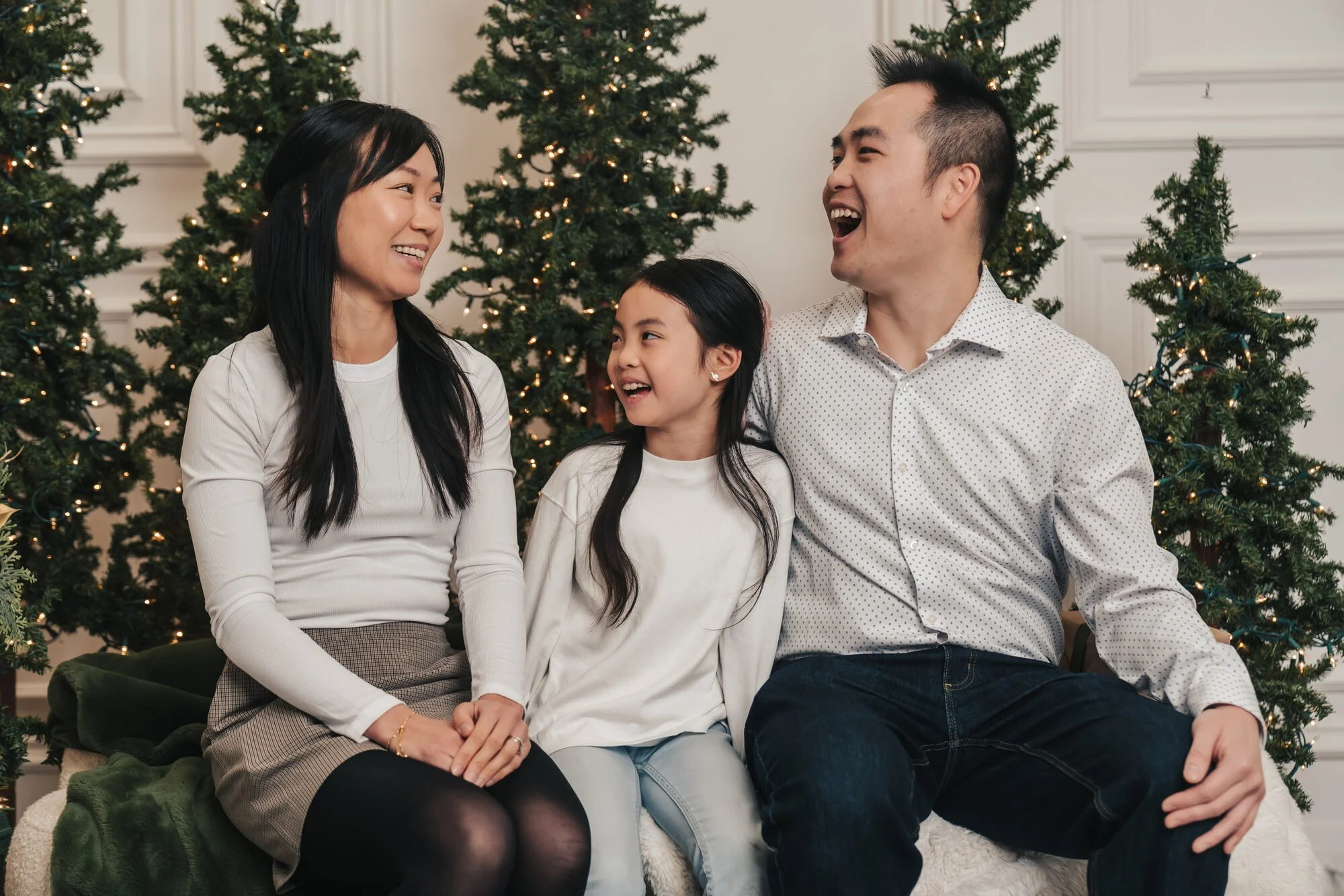 Family of three laughing together at a candid Christmas family photoshoot in Toronto