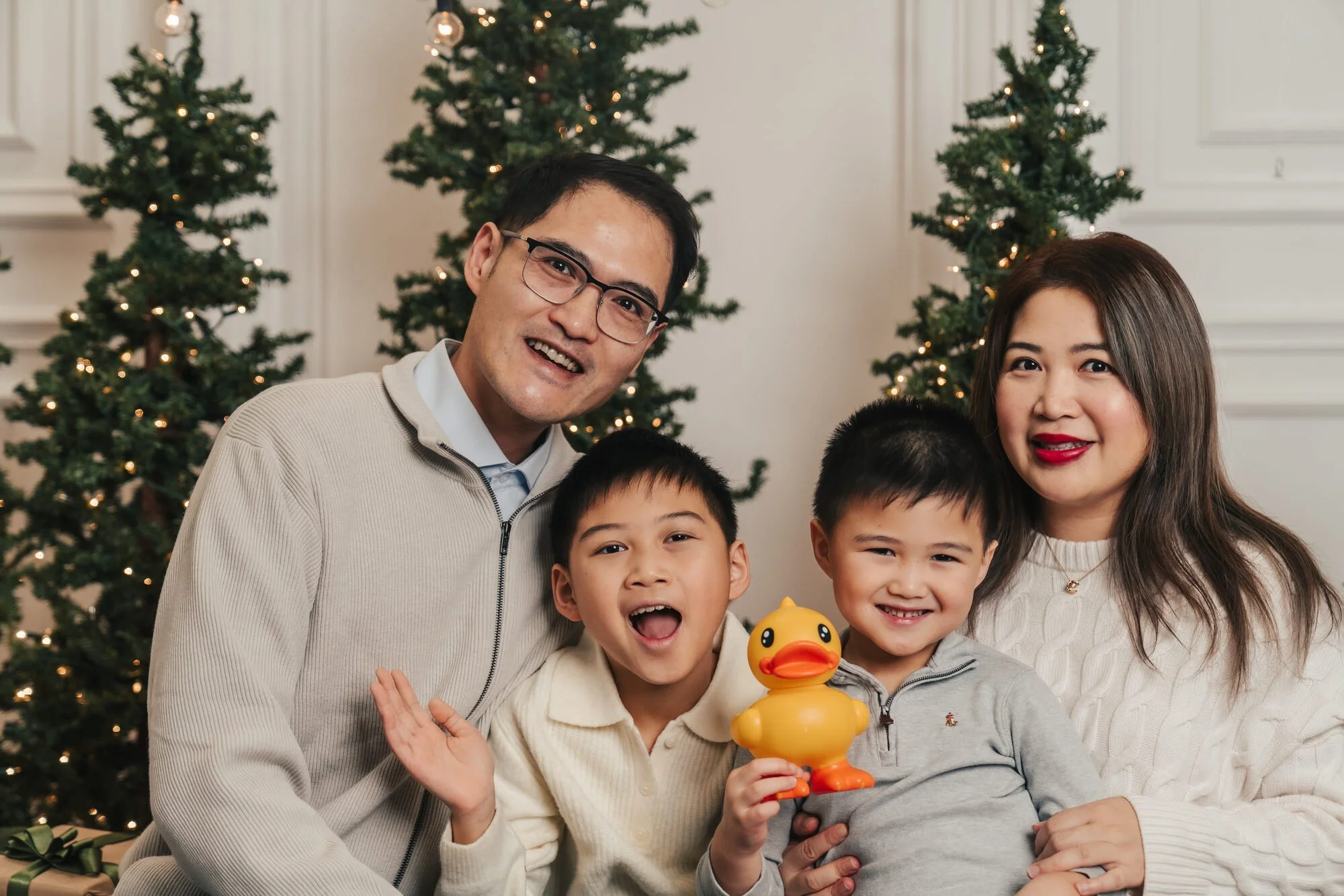 Family in cream knits laughing at a neutral Christmas mini session in the GTA