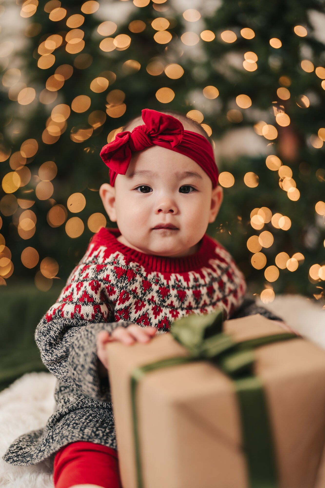 Baby with a wrapped gift at a baby's first Christmas photoshoot in the GTA