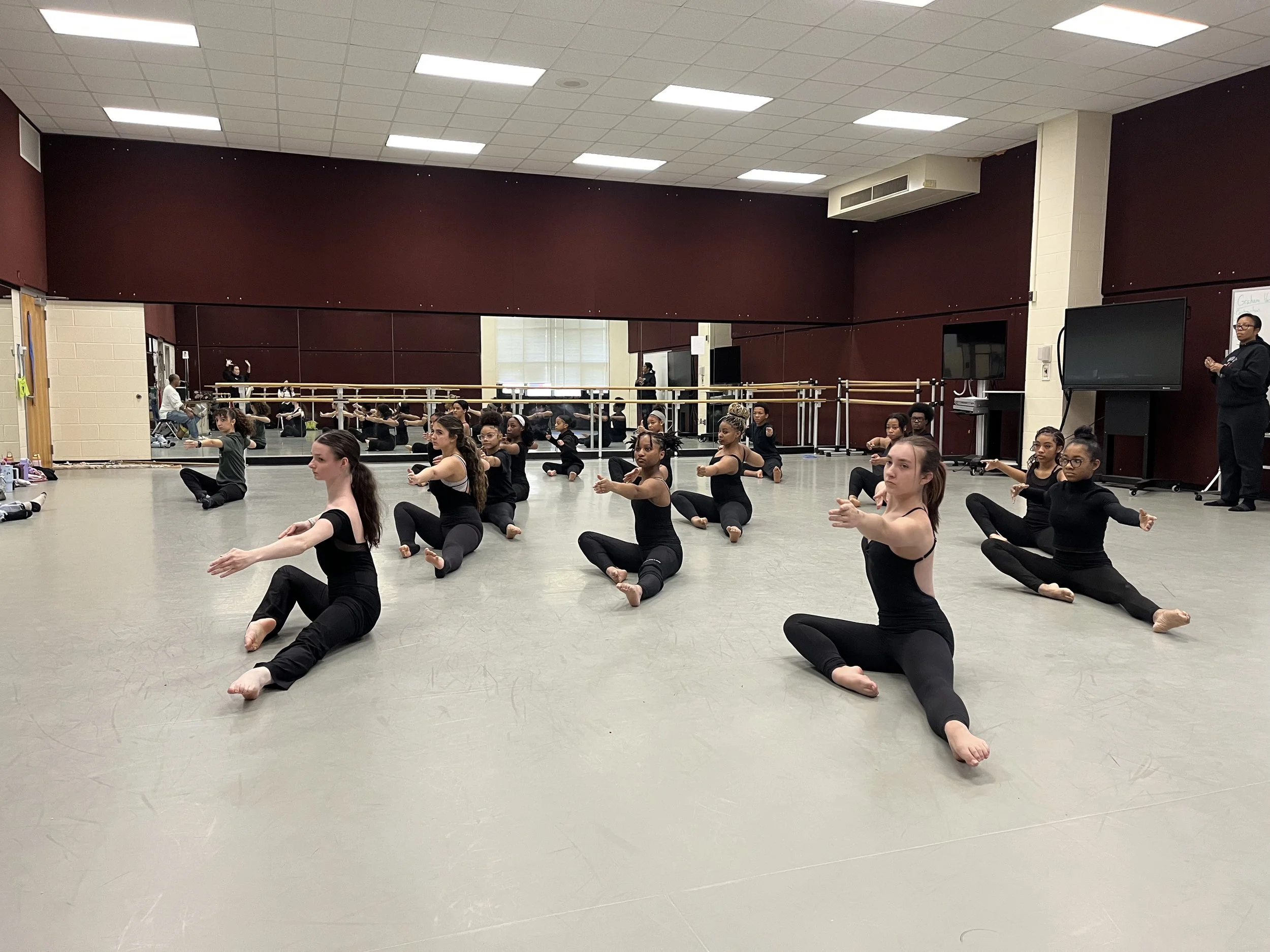 students sitting on the floor of a dance studio