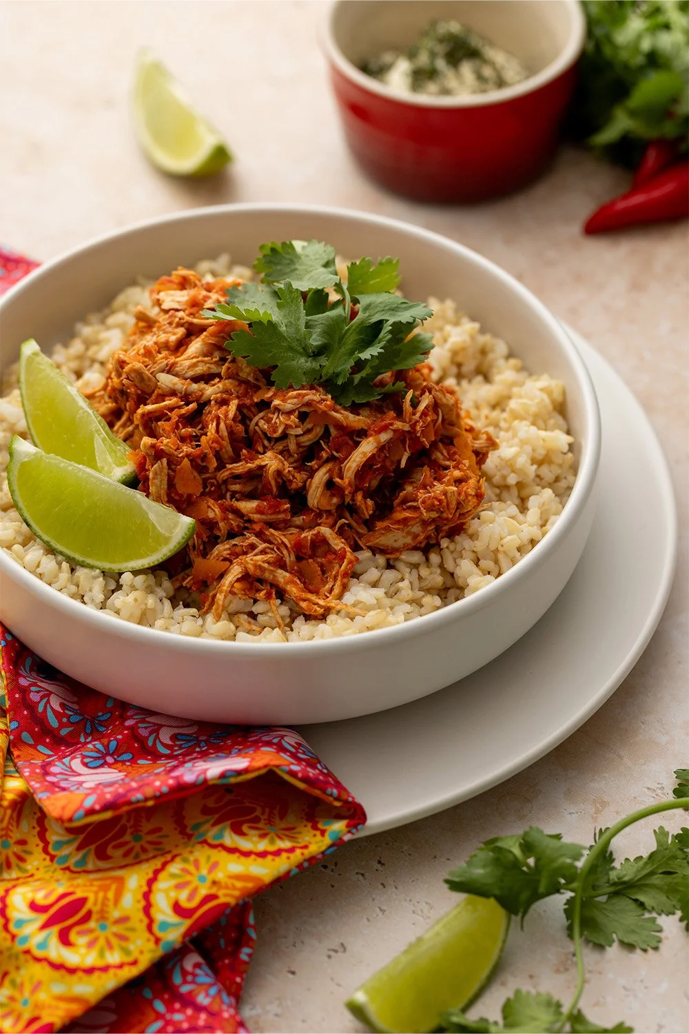 A plate of rice and low FODMAP Chicken Tinga with a garnish of coriander and lime wedges.