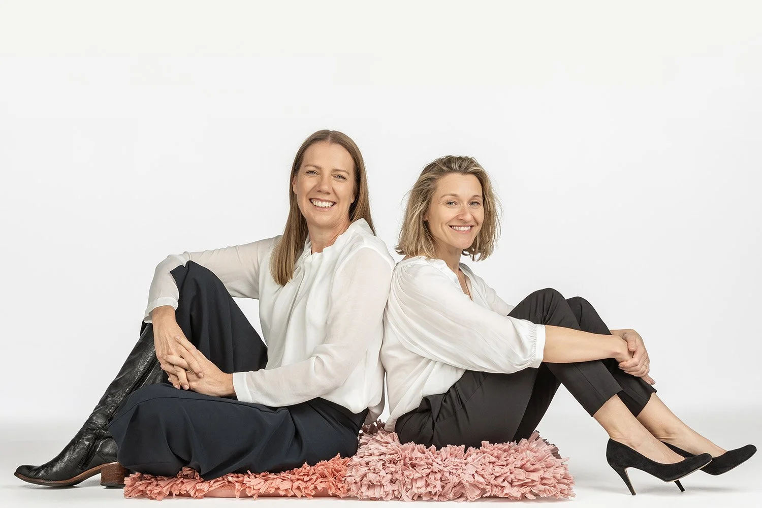 Mary and Josephine sitting back to back on fluffy pink cushions