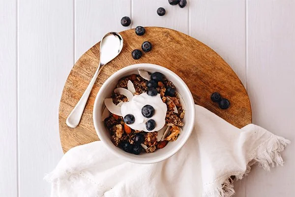 Low FODMAP toasted muesli in a bowl topped with yoghurt and blueberries