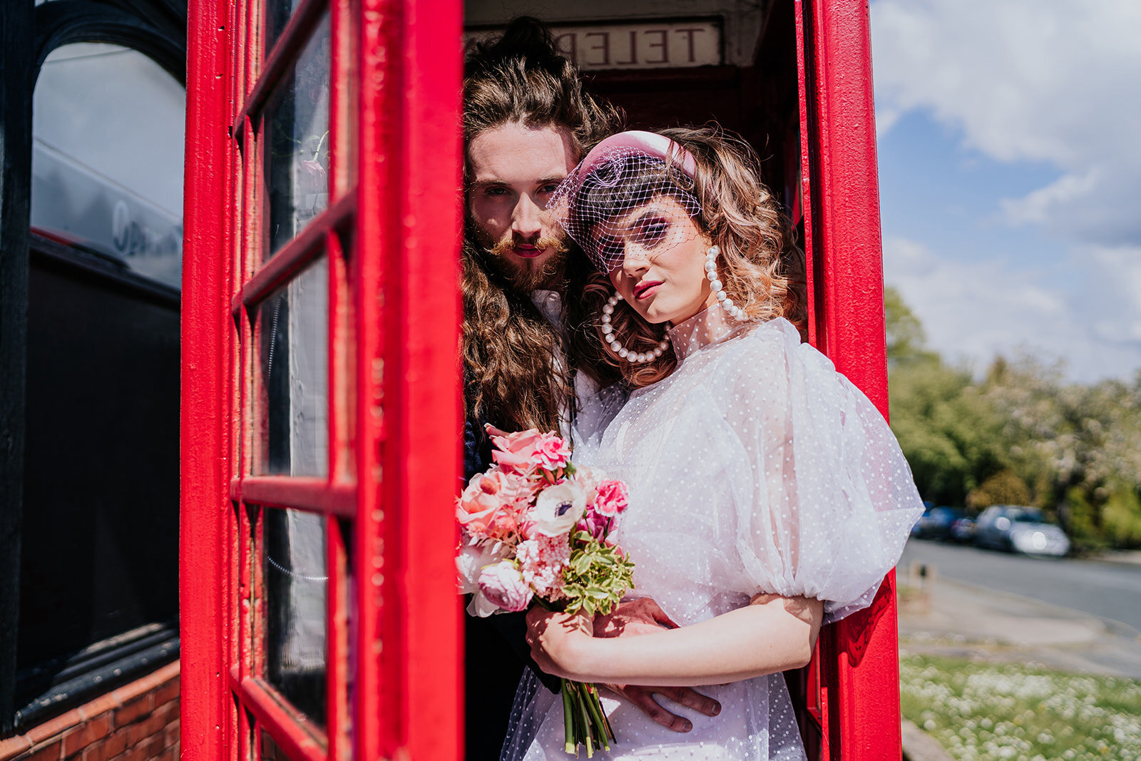 an alternative bride and groom standing in a red telephone box