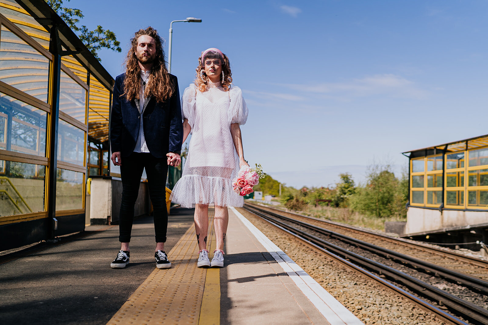 bride and groom standing on the platform of a train station