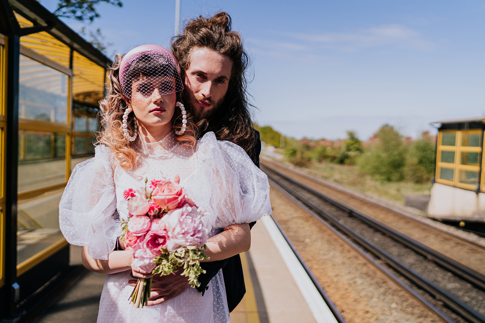 an 80s style bride and groom looking waiting for their train