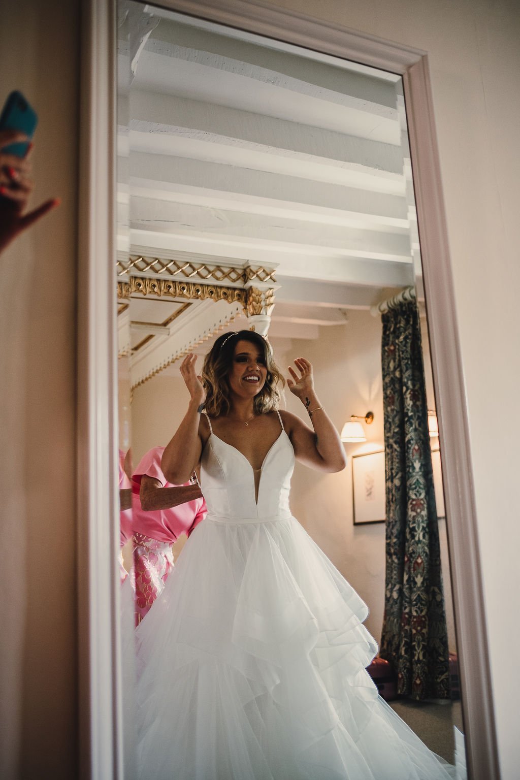 bride sees herself in the mirror for the first time and looks happy