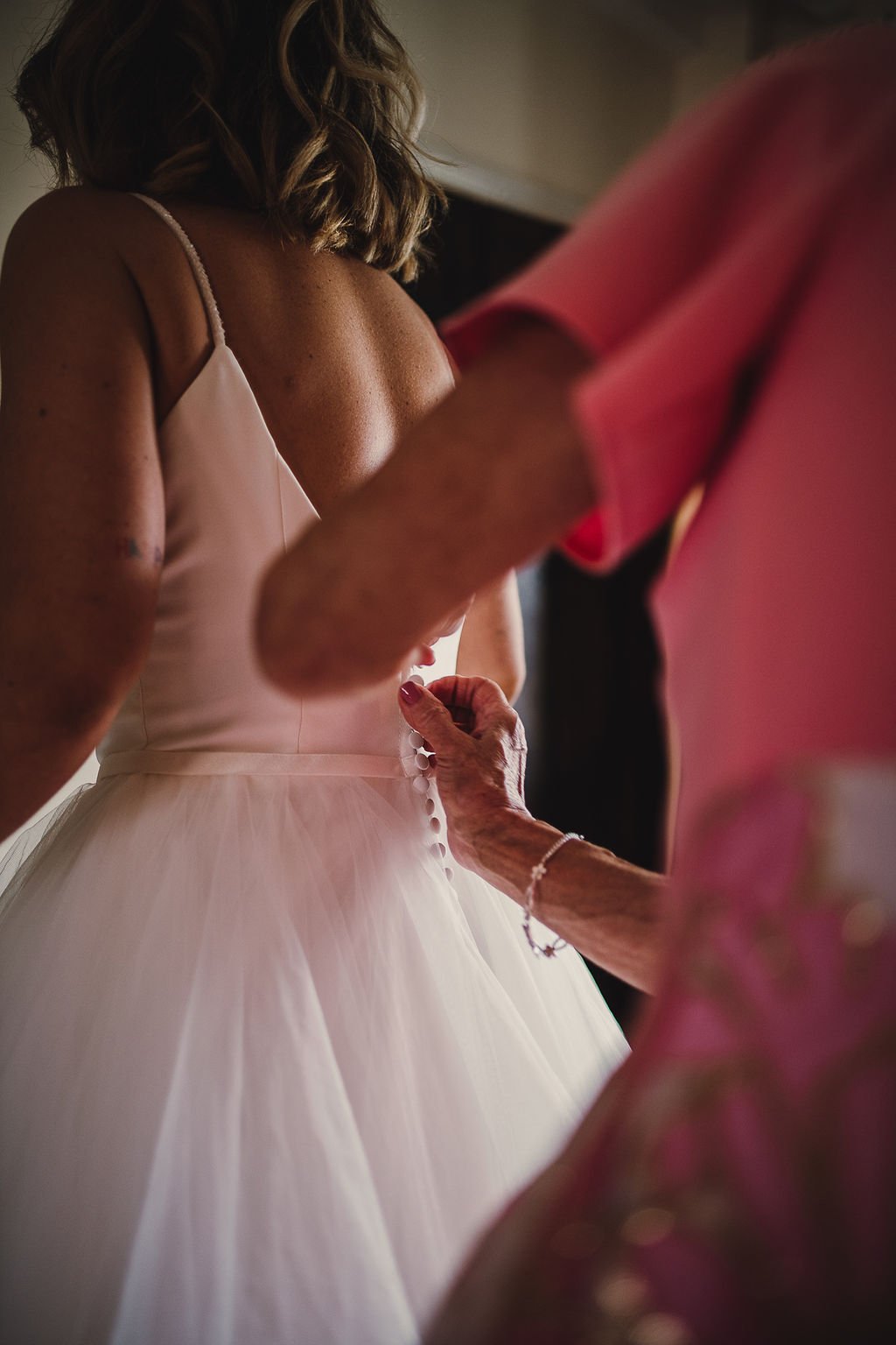 mother of the bride helping daughter with her buttons